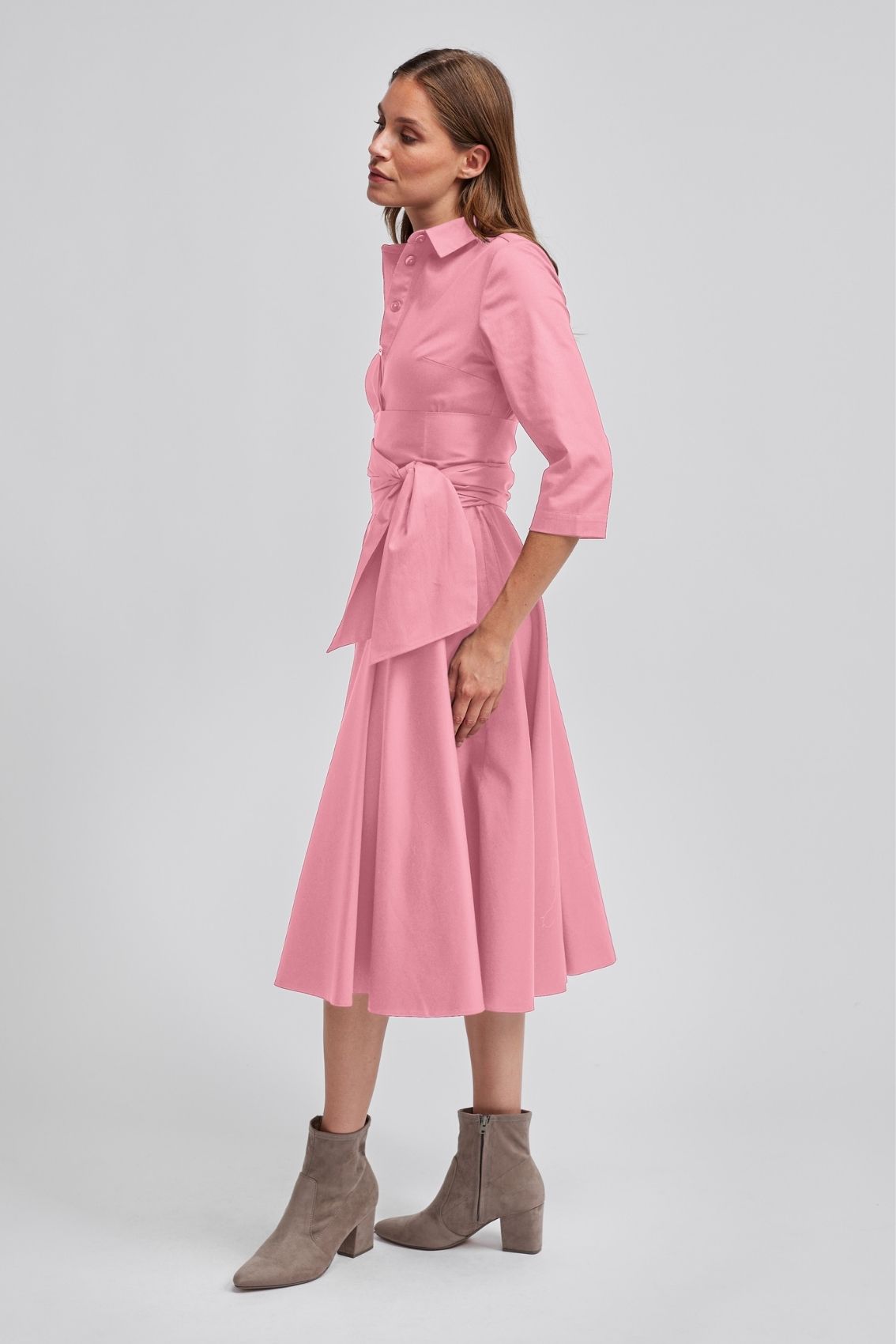 Model trägt roséfarbenes Blusenkleid in Seitenansicht mit taillierendem Bindegürtel und schwingendem Rock.