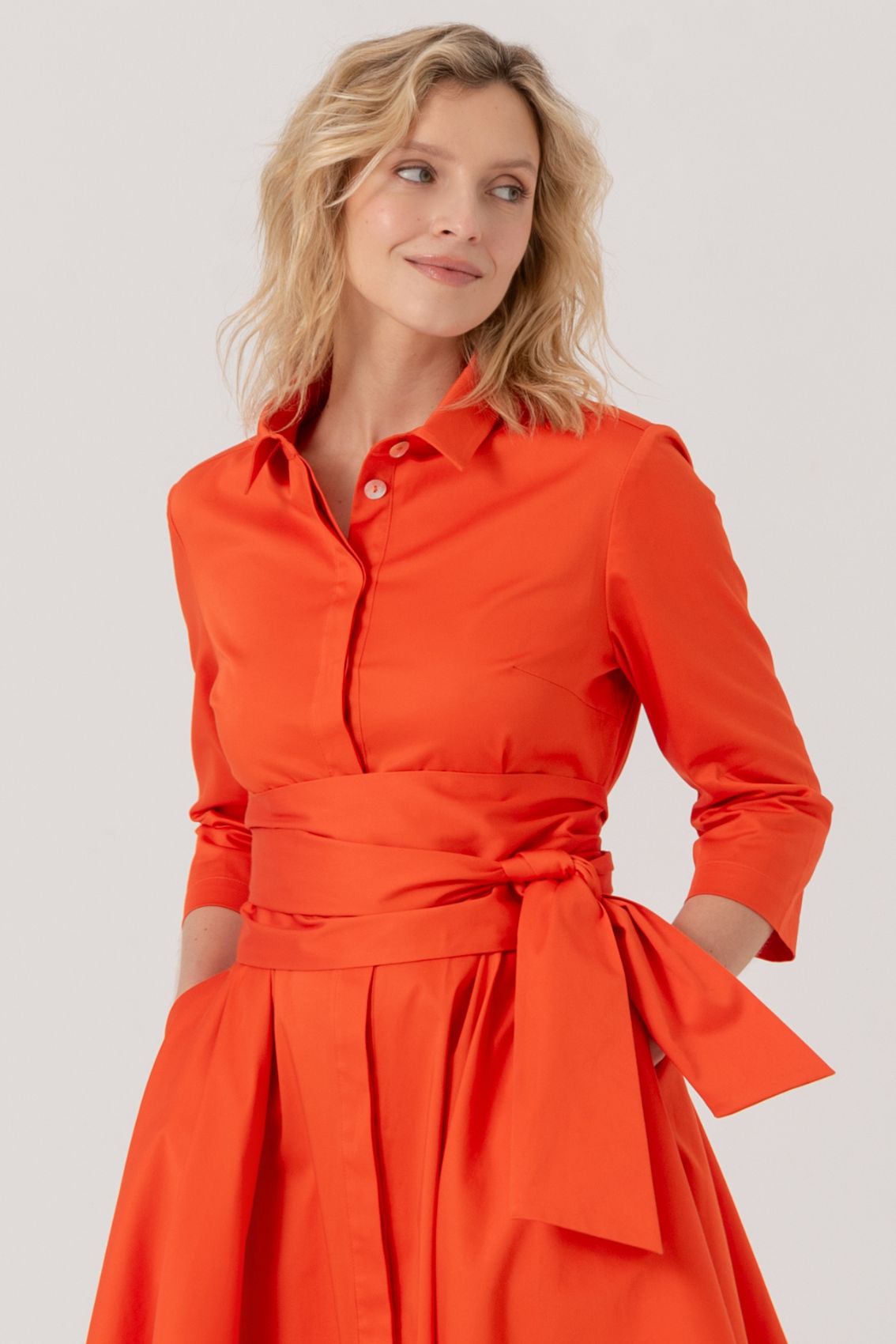Blusenkleid mit Bindegürtel Orange: Elegantes Hemdblusenkleid in leuchtendem Orange mit 3/4-Ärmeln, Spitzkragen, A-Linien-Silhouette und breitem Bindegürtel in der Taille. Seitentaschen und verdeckte Knopfleiste vervollständigen das sommerliche Design.