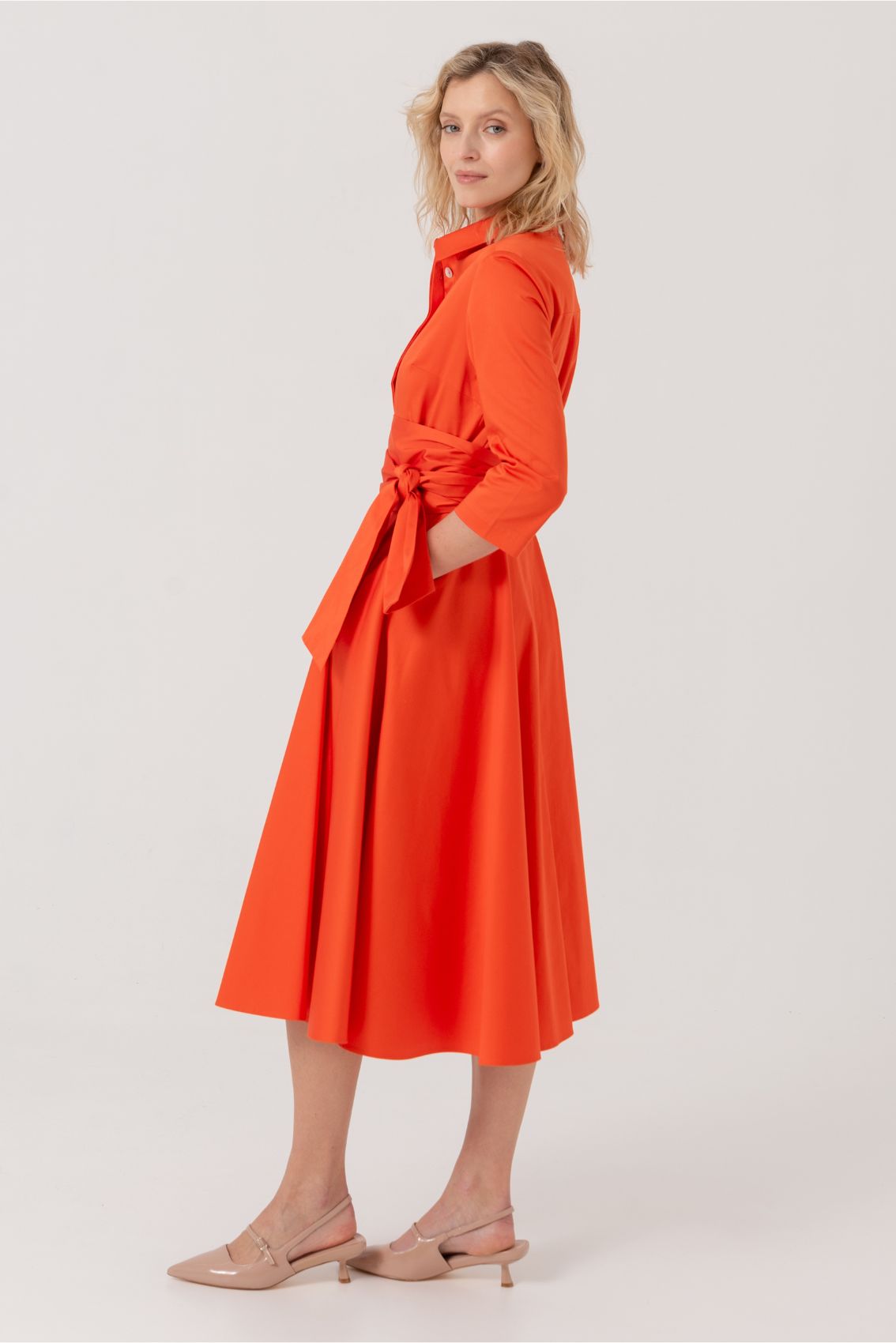 Blusenkleid mit Bindegürtel Orange: Elegantes Midi-Kleid in leuchtendem Orange mit A-Linien-Silhouette, Spitzkragen, 3/4-Ärmeln und breitem Bindegürtel. Seitliche Eingriffstaschen und verdeckte Knopfleiste. Seitliche Ansicht des fließenden Kleides mit klassischem Schnitt.