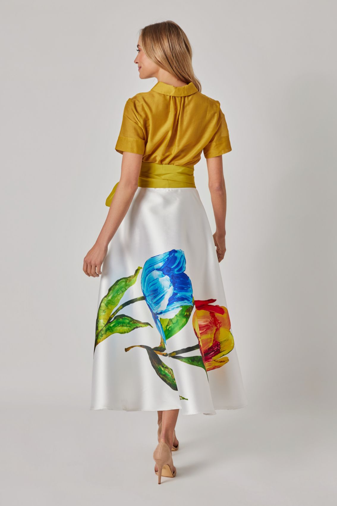 Model trägt Midirock mit Tulpenprint, Rückenansicht, Reißverschluss hinten, Midi-Länge.