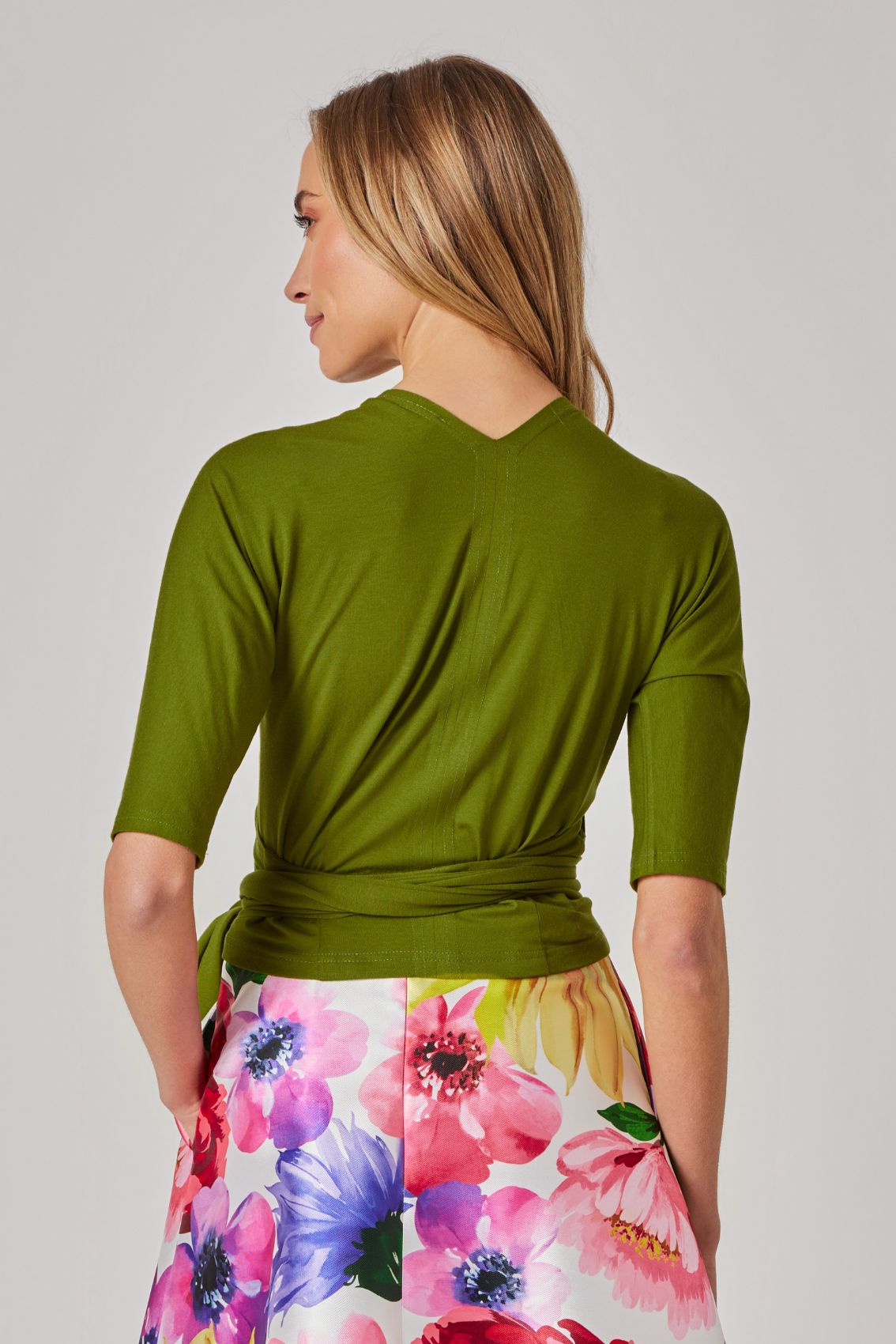 Model trägt limettengrünes Wickeltop, Rückenansicht mit cleanem Fall und 3/4-Ärmeln.