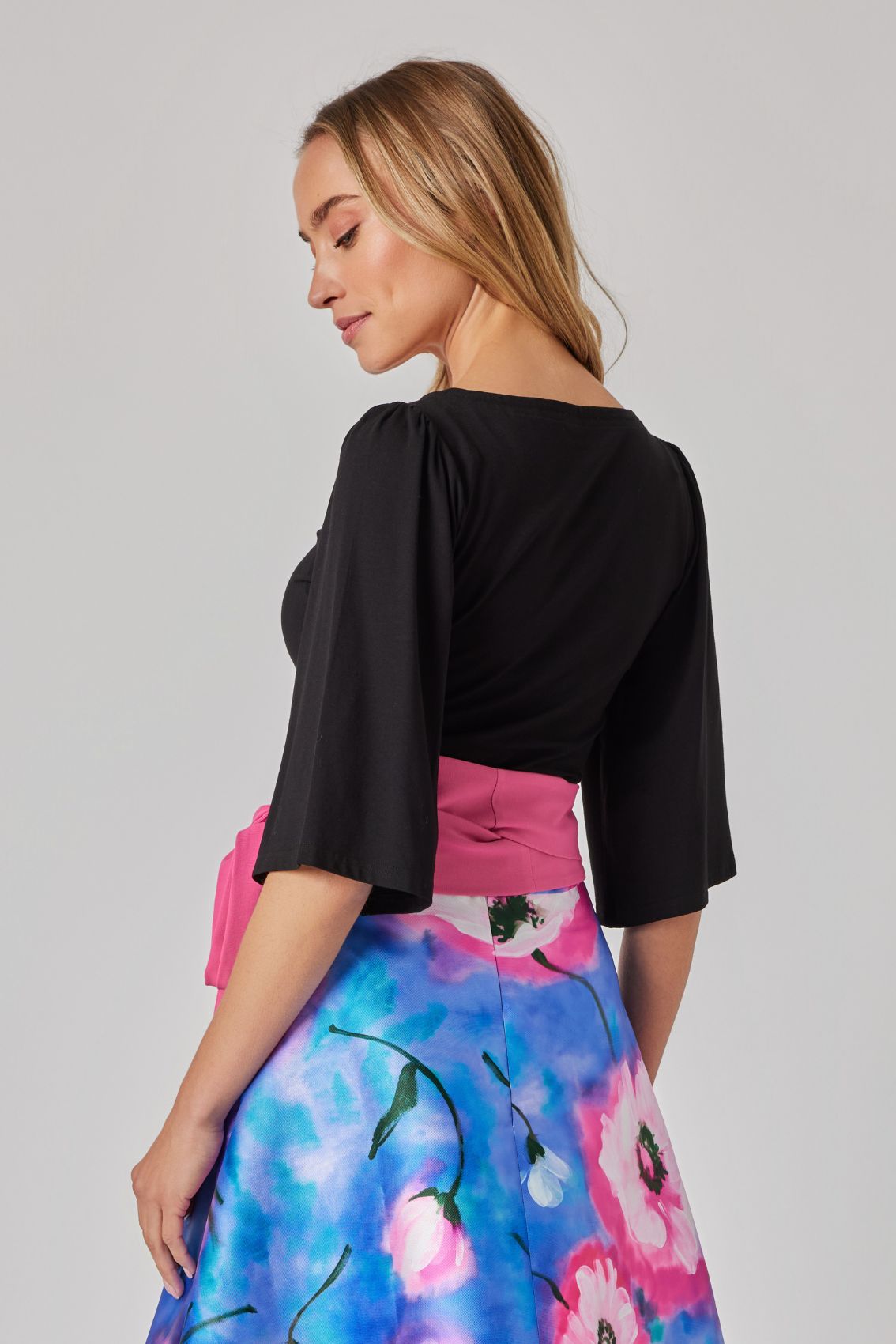 Model trägt schwarzes Shirt, Rückenansicht mit weich fallenden 3/4-Ärmeln und cleanem Look.