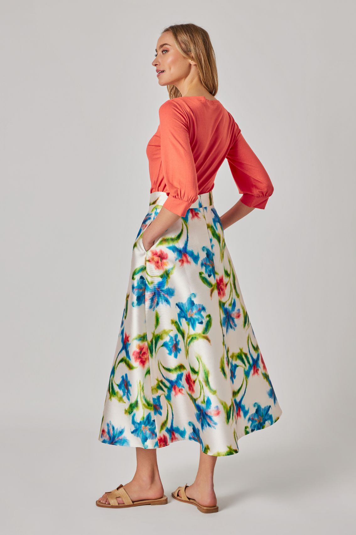 Model trägt Midirock „Kornblumenprint“, Rückenansicht der A-Linie in Midi-Länge.