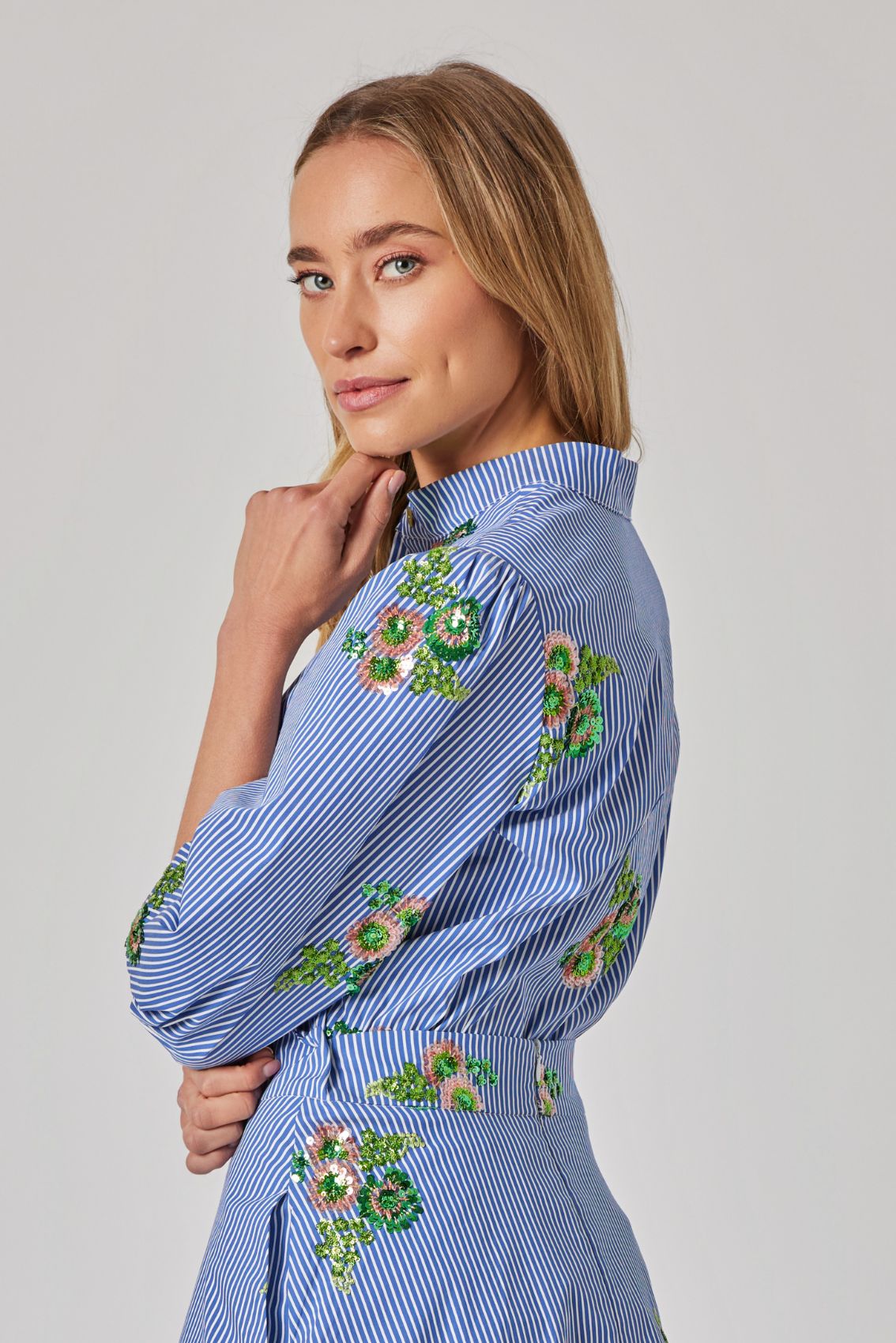 Model trägt die Bluse mit Paillettenblüten, Rückenansicht, lockerer Fall am Saum.