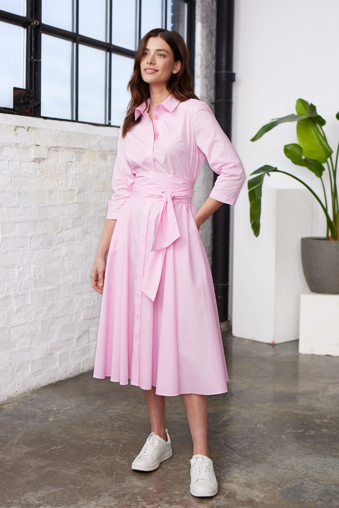 Model trägt rosafarbenes Blusenkleid mit Kragen, Bindegürtel und Seitentaschen, Frontansicht