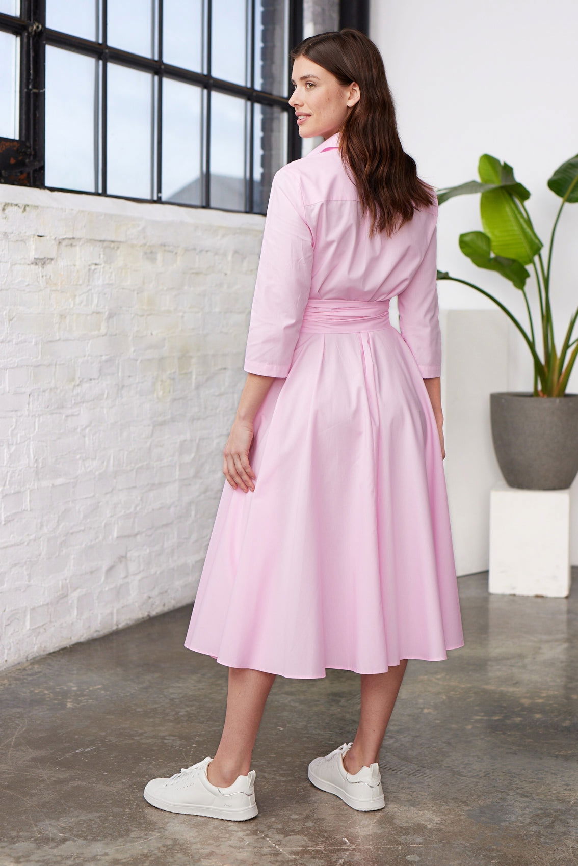 Model trägt rosafarbenes Blusenkleid in A-Linie mit Bindegürtel und 3/4-Ärmeln, Rückenansicht