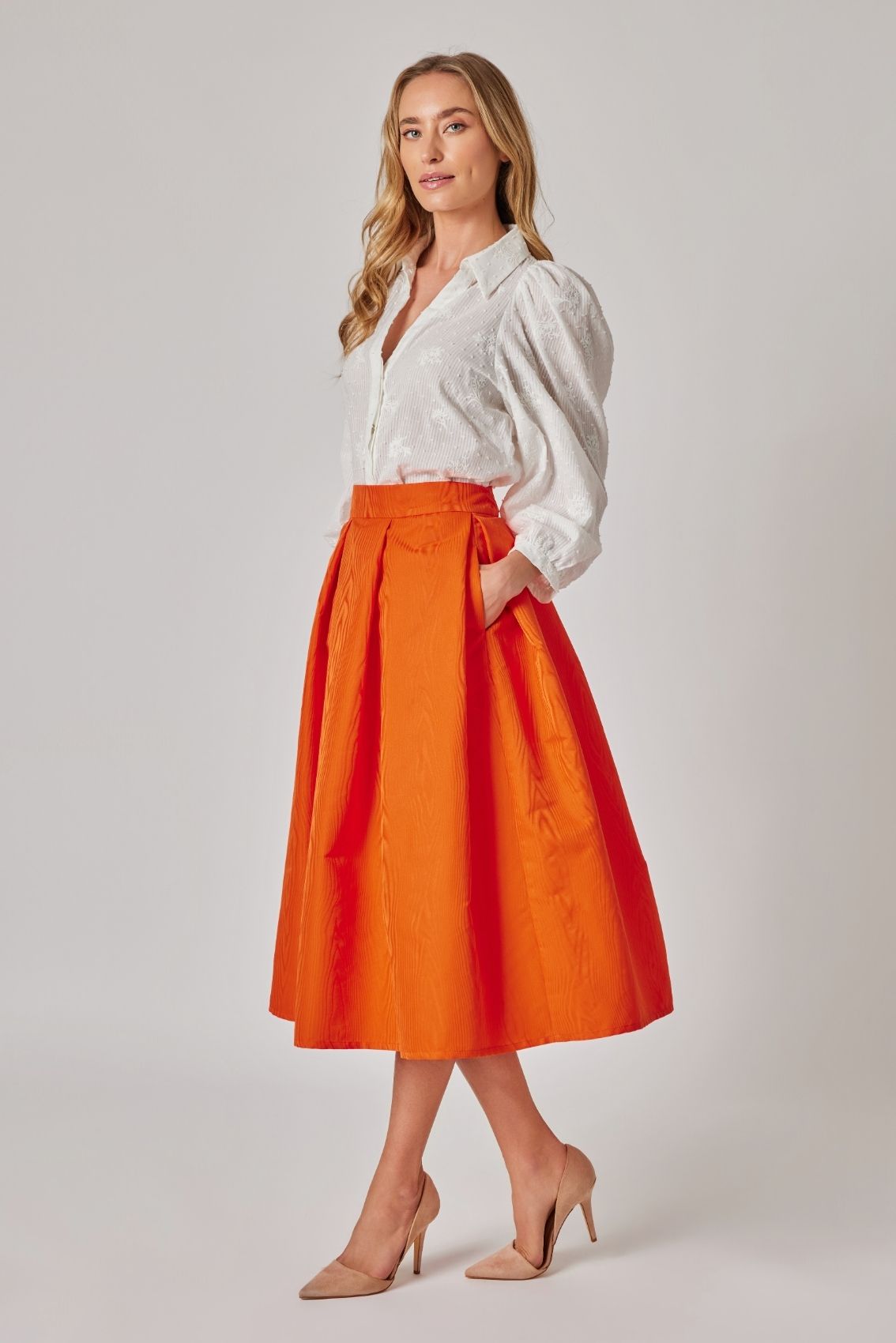 Model trägt Midirock in Orange, Rückenansicht mit Reißverschluss hinten und weich fallender Silhouette.