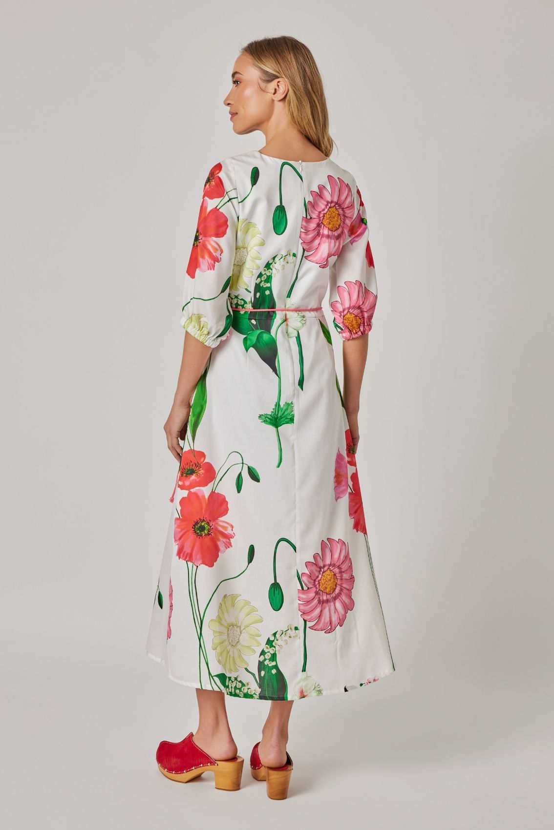 Model trägt florales Midikleid mit 3/4-Ärmeln und Reißverschluss hinten, Rückenansicht.
