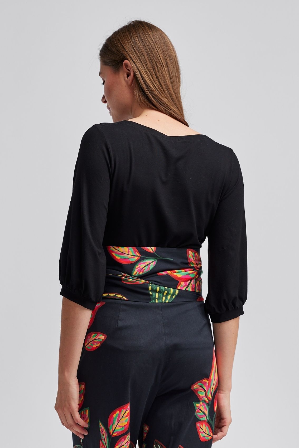 Model trägt schwarzes Shirt mit sehr lockeren 3/4-Ärmeln, Rückenansicht.