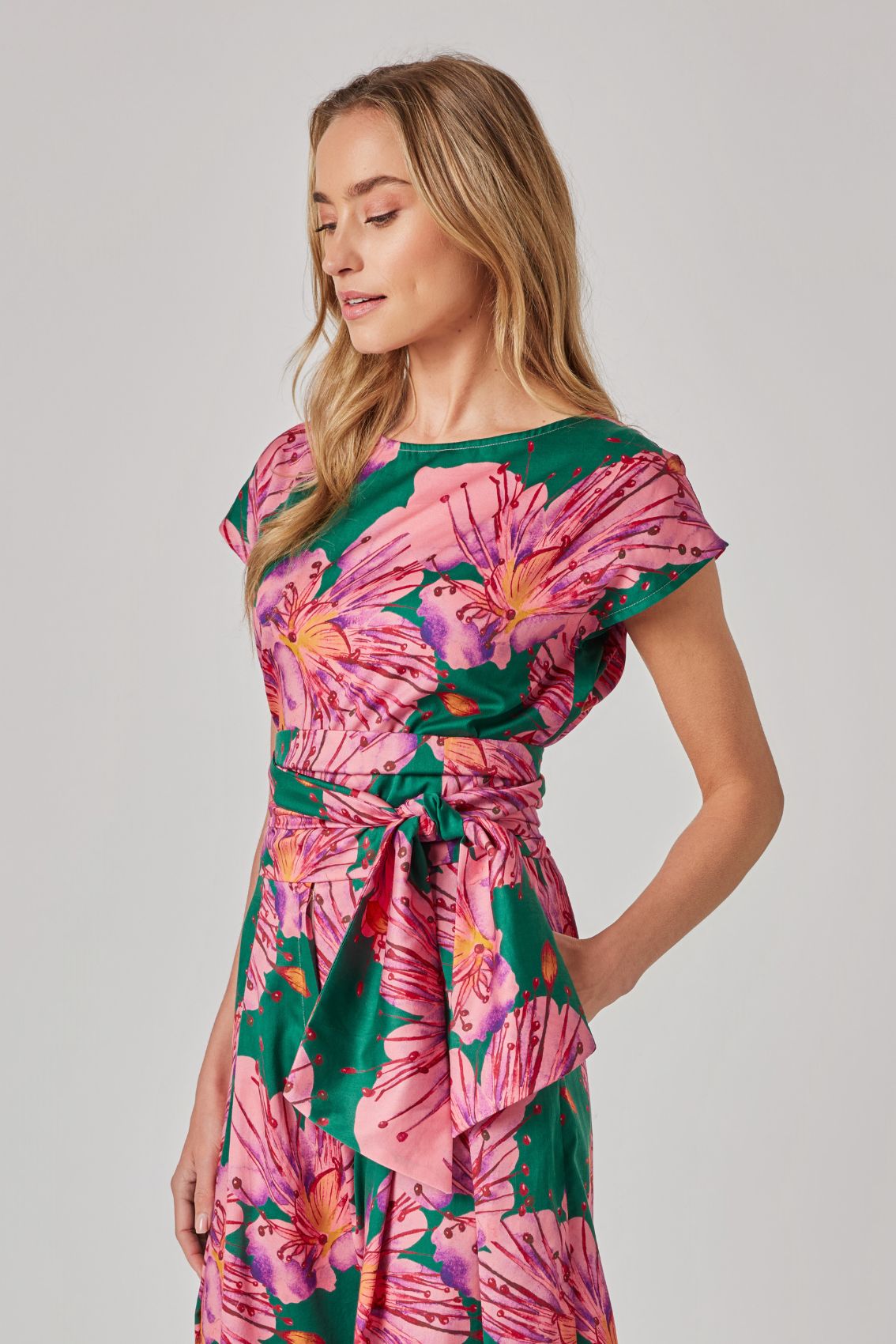 Model trägt Oberteil mit kurzen Ärmeln und großem Blumenprint, Seitenansicht.