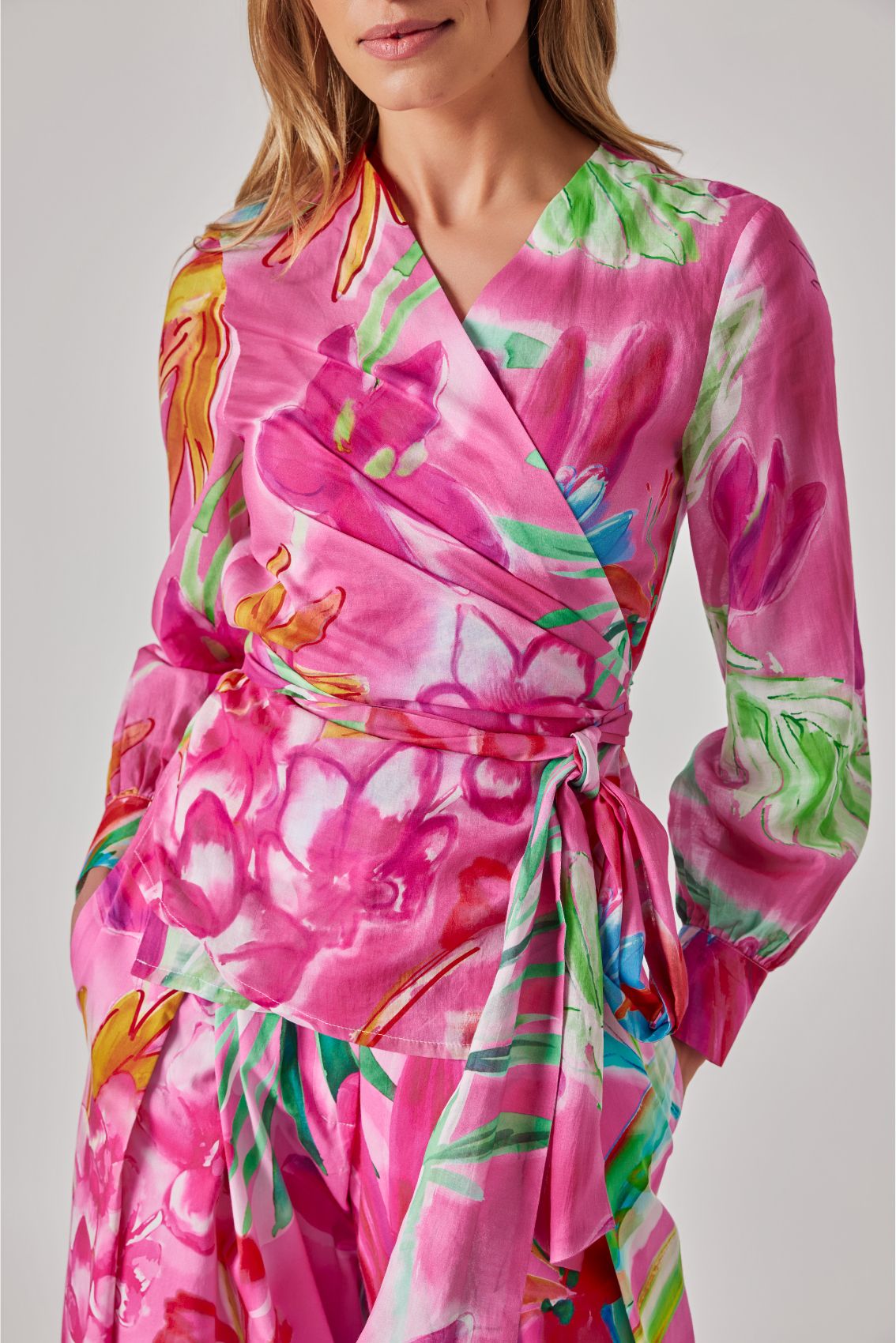 Close-up des pinken Wickeloberteils mit Bindegürtel und Aquarell-Blumenprint, Detailansicht.