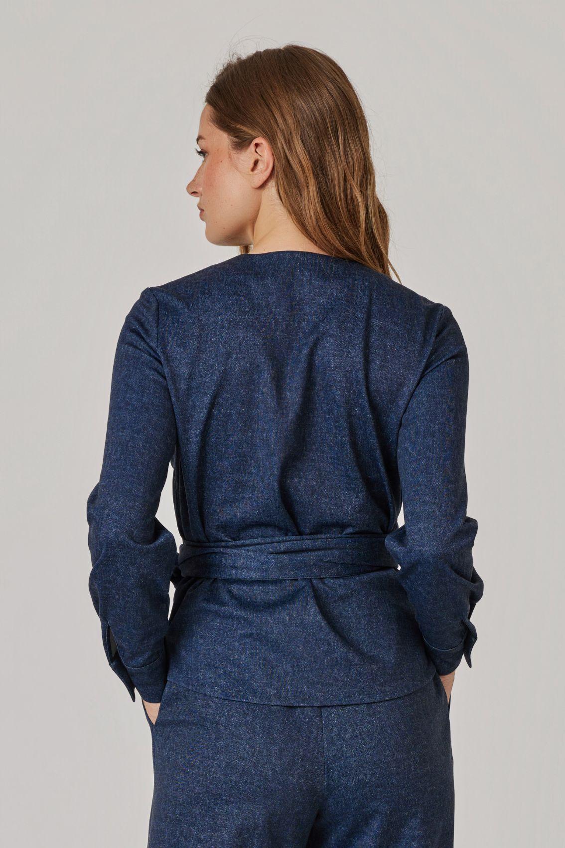 Model trägt Bluse in Denim-Blau, Rückenansicht mit umlaufendem Bindegürtel an der Taille.