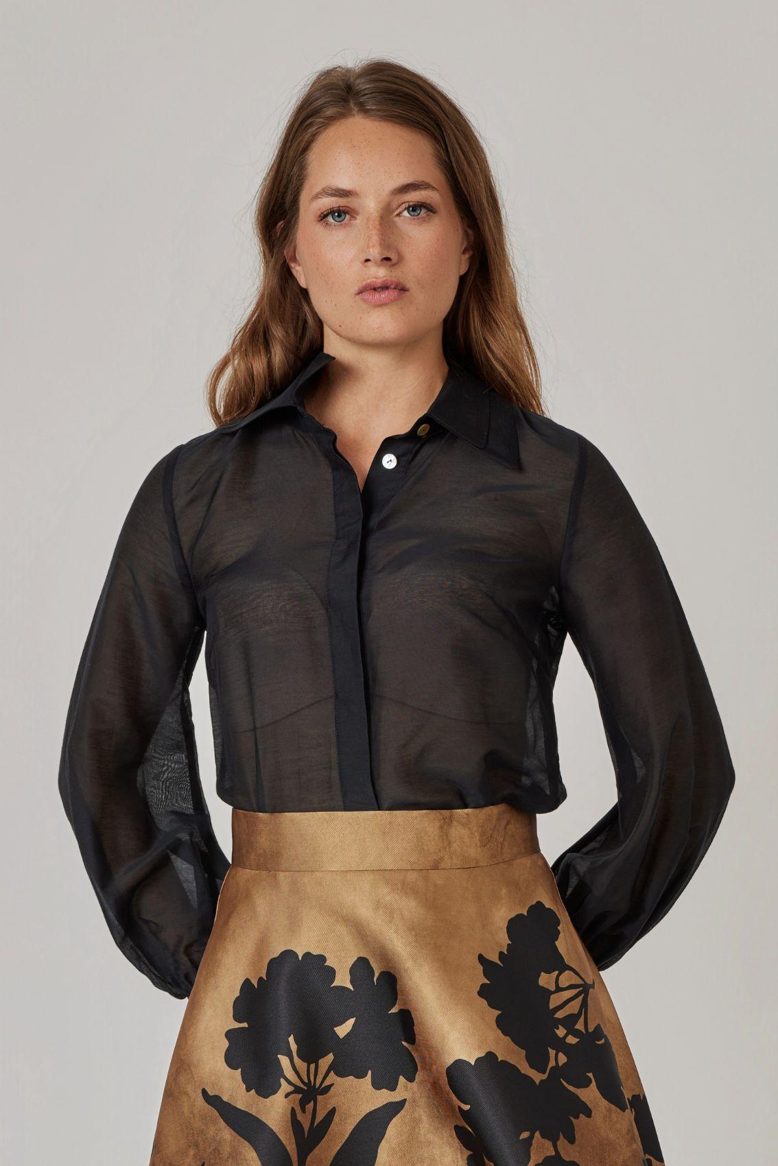 Model trägt schwarze Bluse mit strukturiertem Doppelkragen und offenem Ausschnitt, Frontansicht.