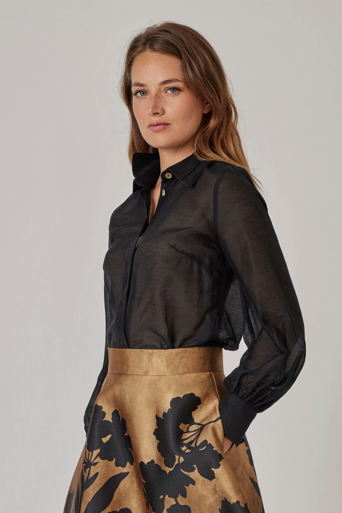 Model trägt schwarze Bluse mit Ballonärmeln und Manschette, Seitenansicht.