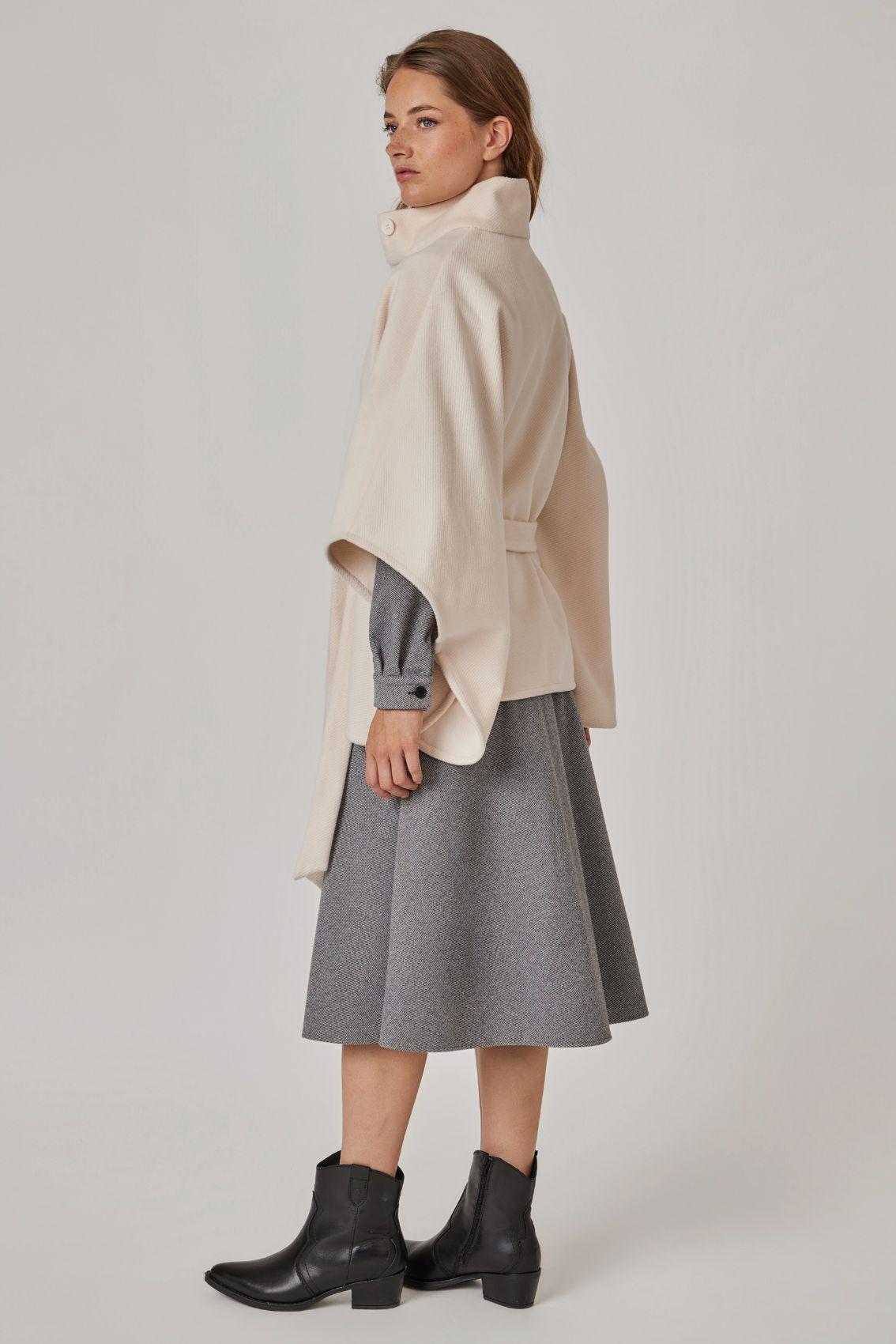Model trägt Cape Creme, Seitenansicht mit weitem Ärmelschnitt.