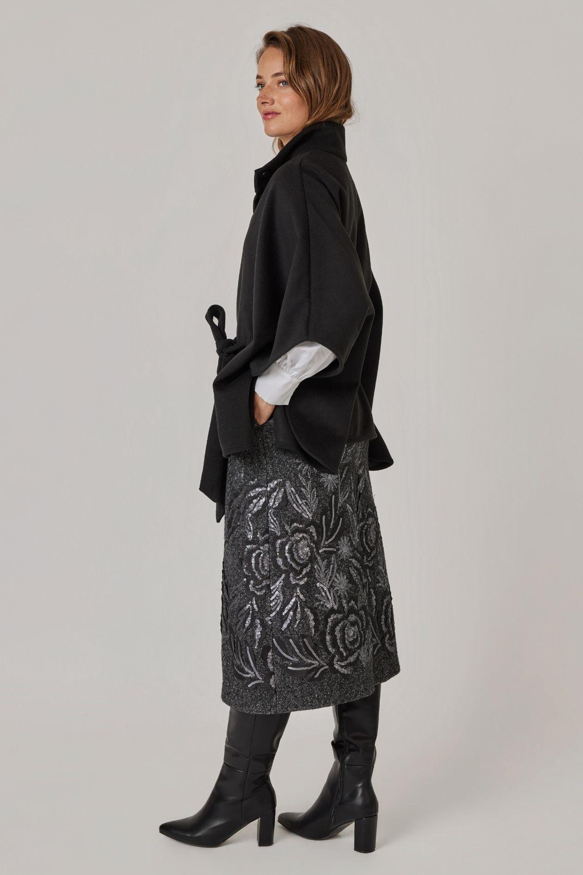 Model trägt Cape Schwarz, Seitenansicht mit weitem Ärmelschnitt.
