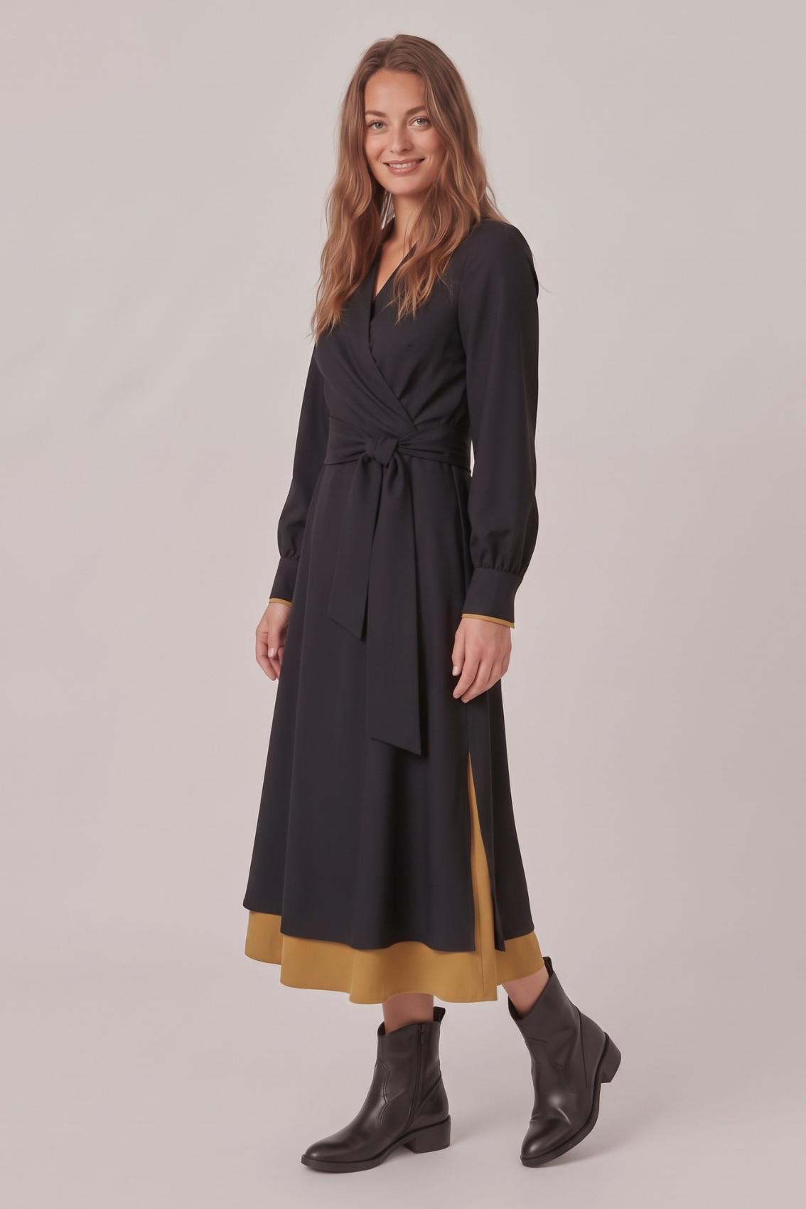 Model trägt schwarzes Midikleid mit Ballonärmeln, schräge Seitenansicht mit Unterrock in Safrangelb.
