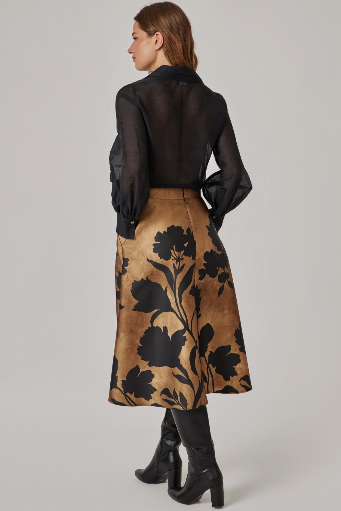 Model trägt Rock mit Blüten-Scherenschnitt-Print, Rückansicht mit verdecktem Reißverschluss in der hinteren Mitte.