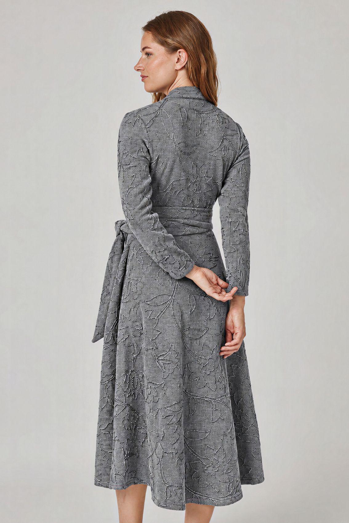 Model trägt graues Kleid mit Blumenstickerei, Rückansicht mit weit ausgestelltem Rock.
