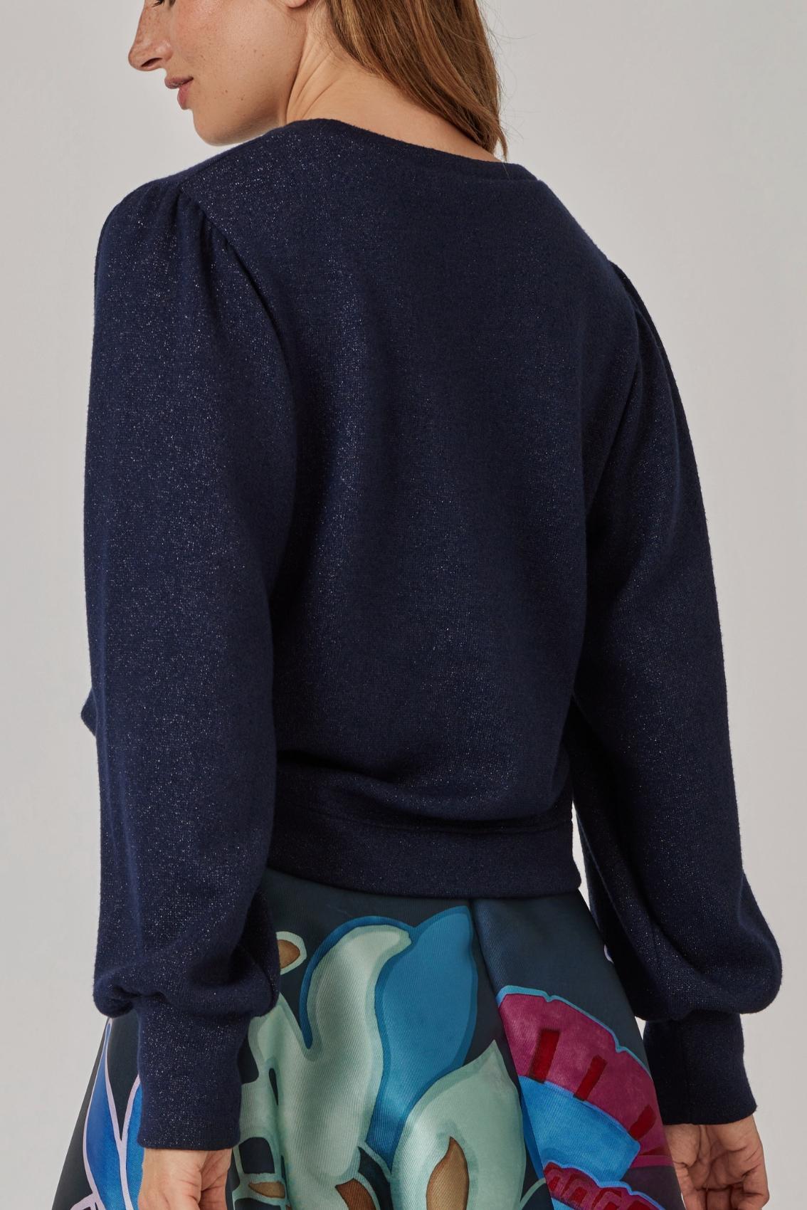 Model trägt navyfarbenen Pullover mit Glitzer, Rückenansicht mit Puffärmeln und gerader Saumblende.