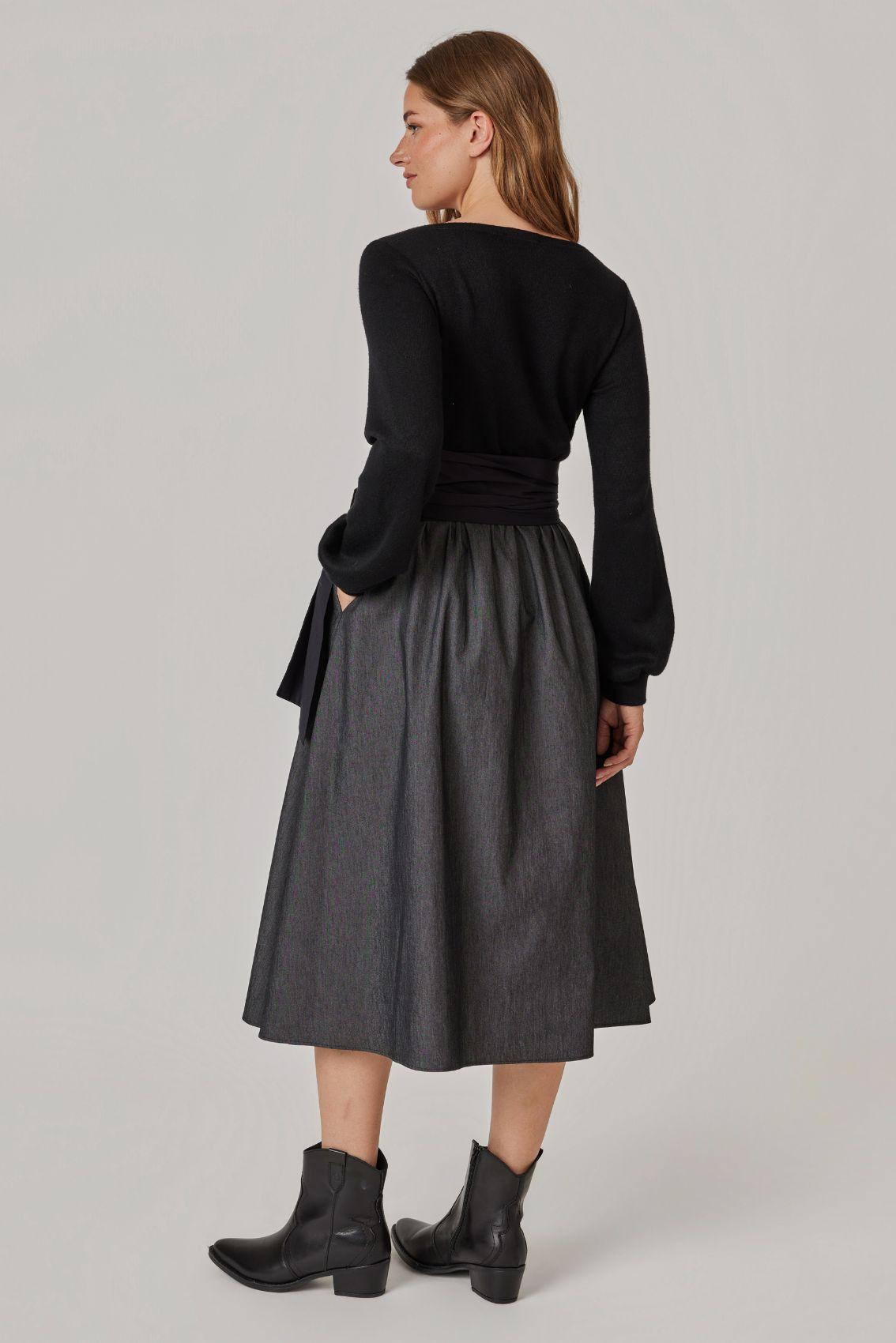 Model trägt Strick-Mix-Kleid, Rückansicht mit fließend fallendem Rock.
