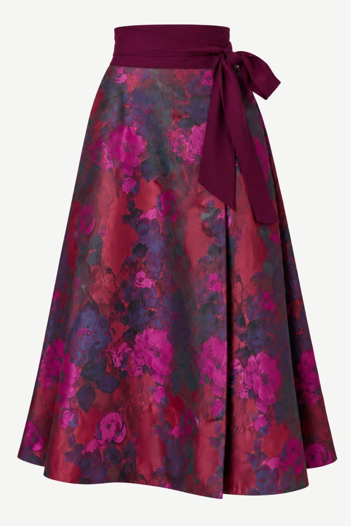 Wendewickelrock mit Rosen-Jacquard in Magenta und Bordeaux, Bindegürtel in Aubergine seitlich zur Schleife gebunden, Frontansicht.