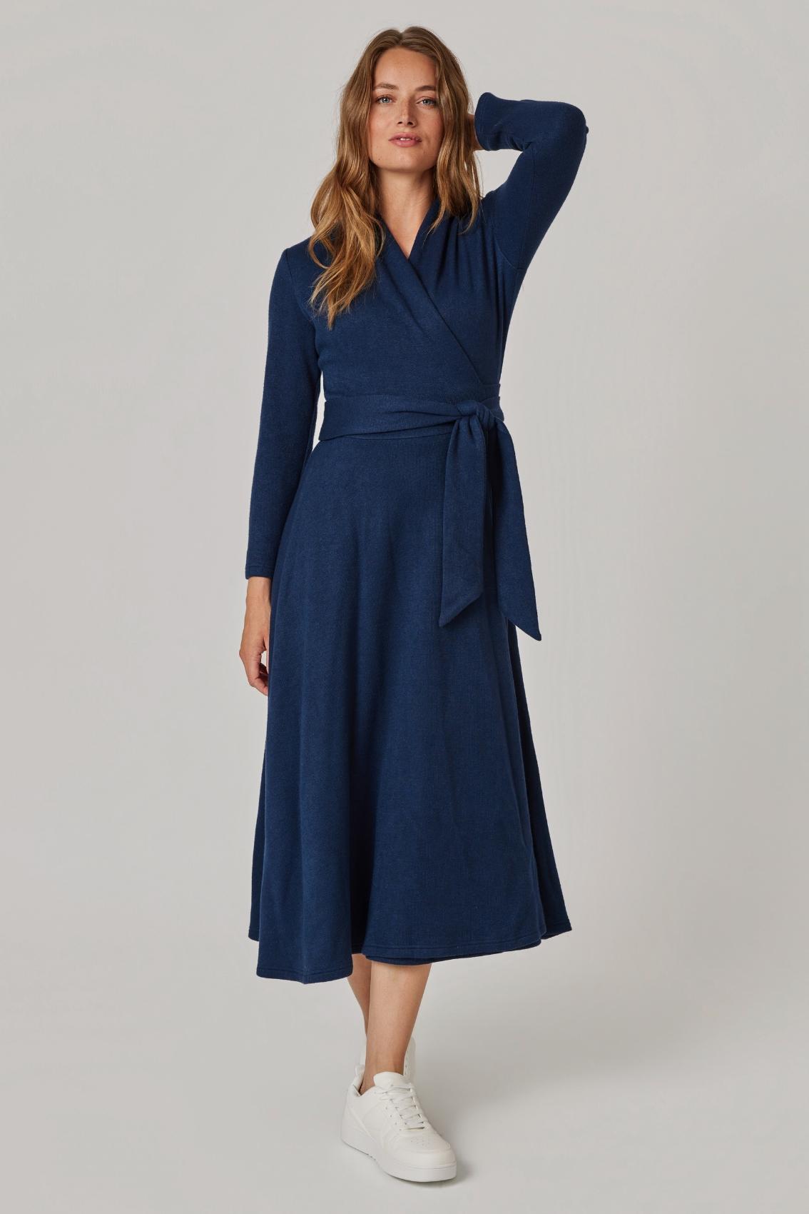 Model trägt Strick Wickelkleid in Navy mit gebundenem Bindegürtel, Frontansicht.