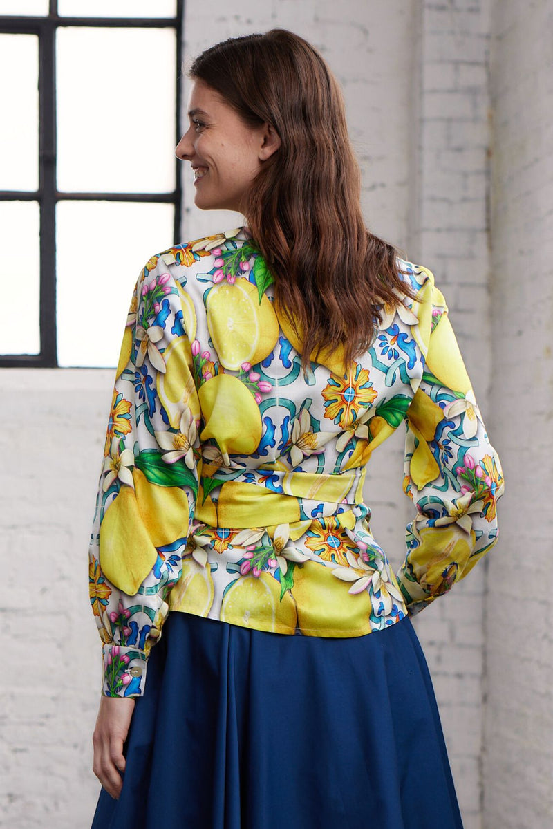 Modell in Rückenansicht trägt eine Wickelblusen mit Zitronen-Print
