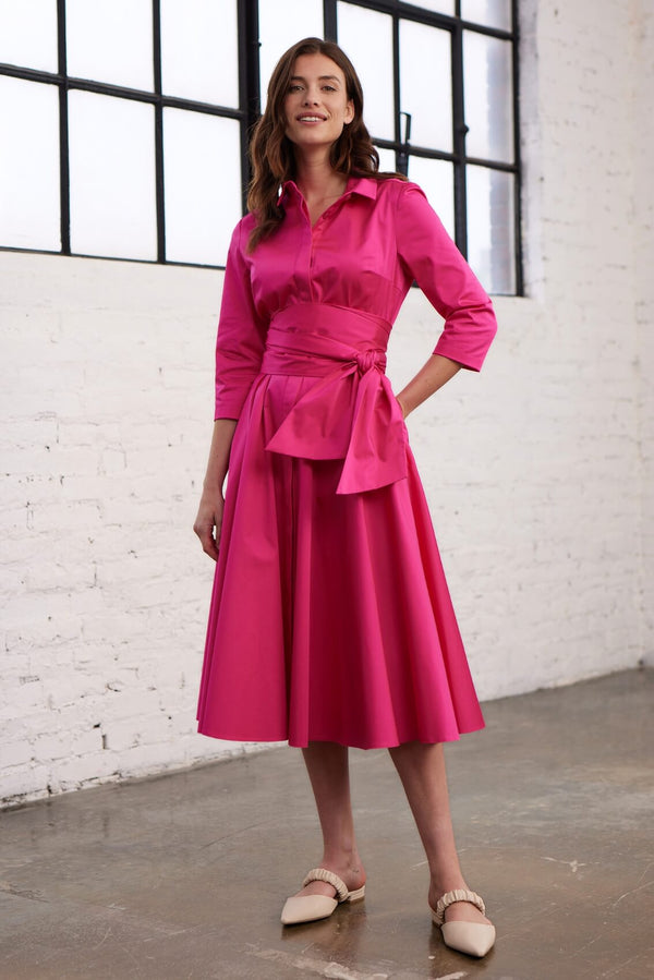 Modell trägt ein Blusenkleid mit Bindegürtel in einem leuchtenden Pink in Vorderansicht