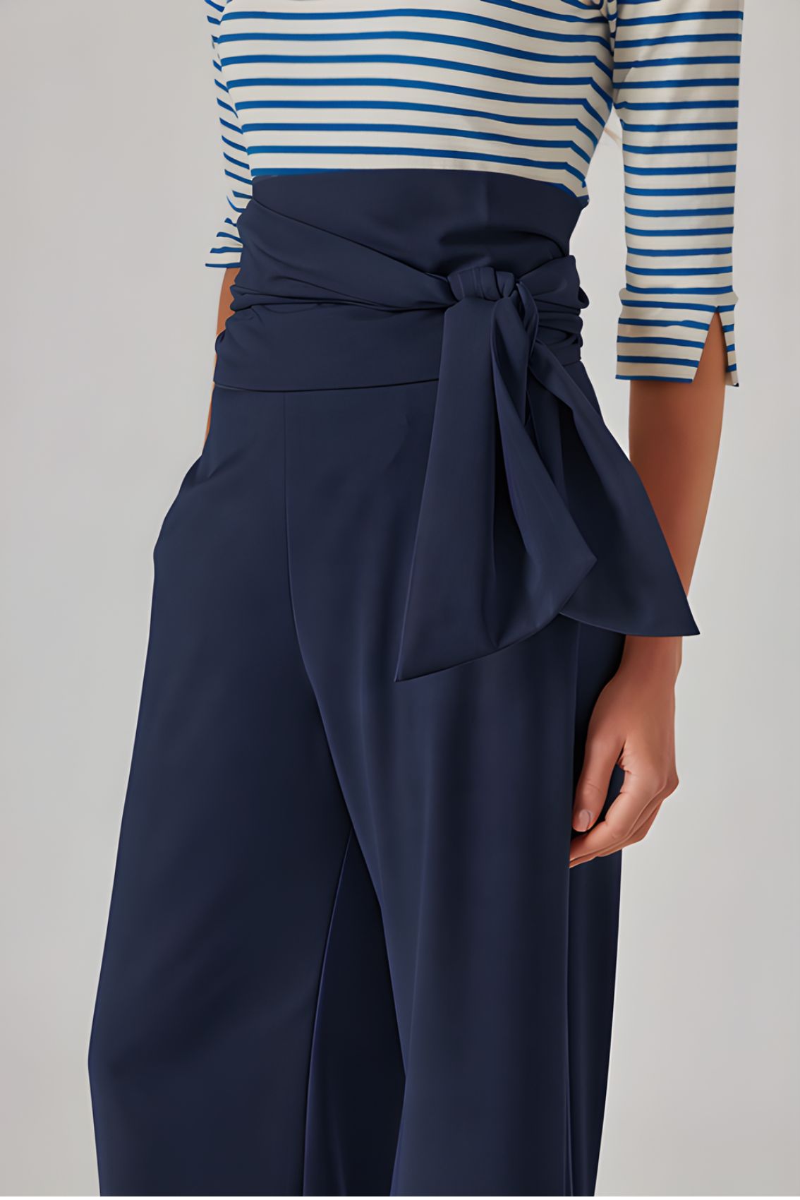 Detailansicht der blauen Wide-Leg Hose mit drapiertem Bindegürtel und glattem, fließendem Stoff.