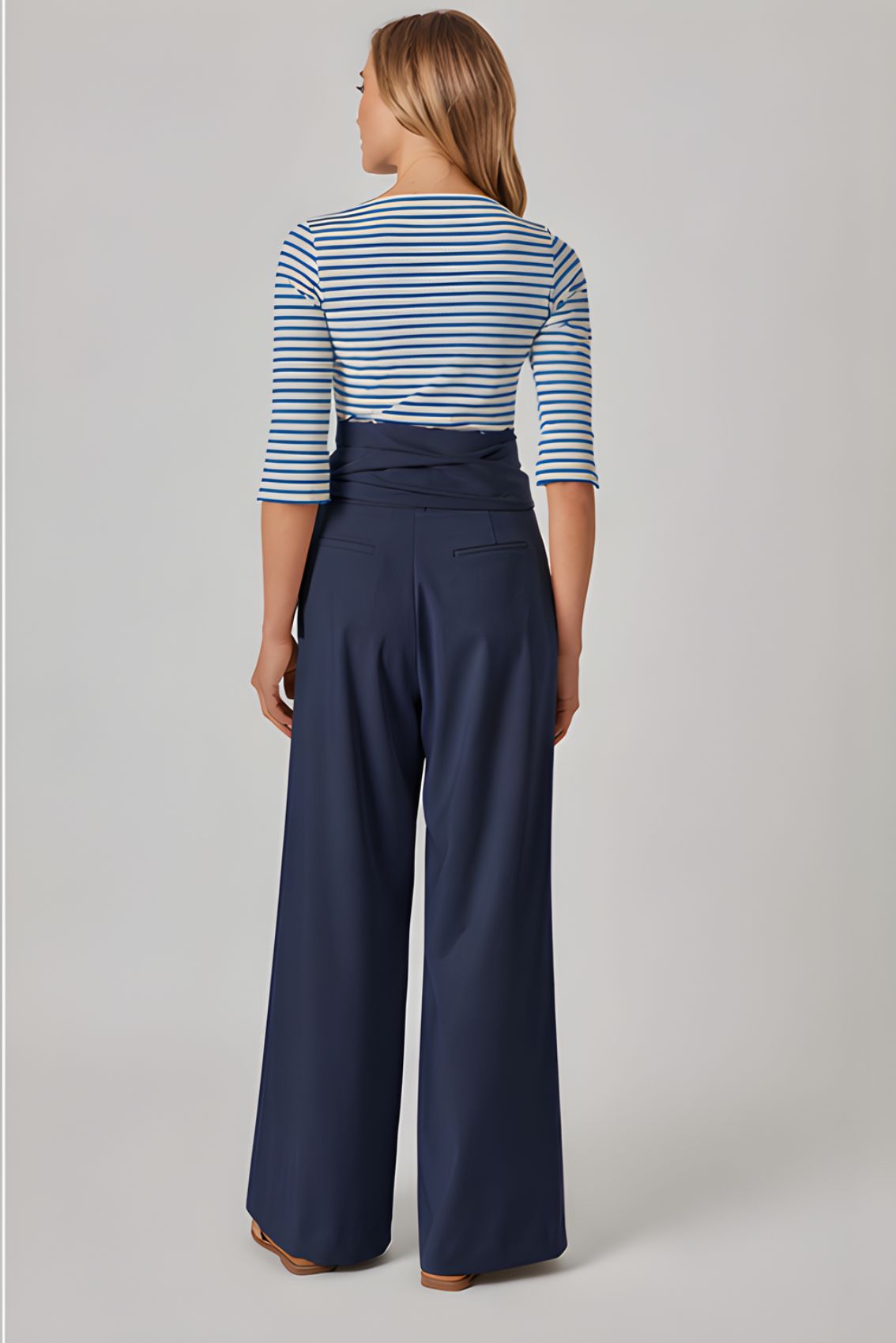 Model trägt blaue Wide-Leg Hose mit hohem Bund und Bindegürtel, Rückenansicht mit weitem Beinverlauf.