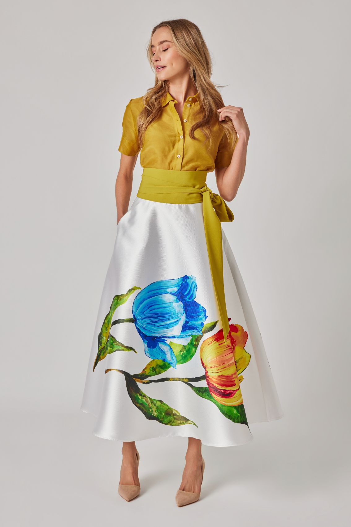 Detailaufnahme Tulpenprint am Rocksaum, malerisches Blumenmotiv mit Blättern auf hellem Grund.