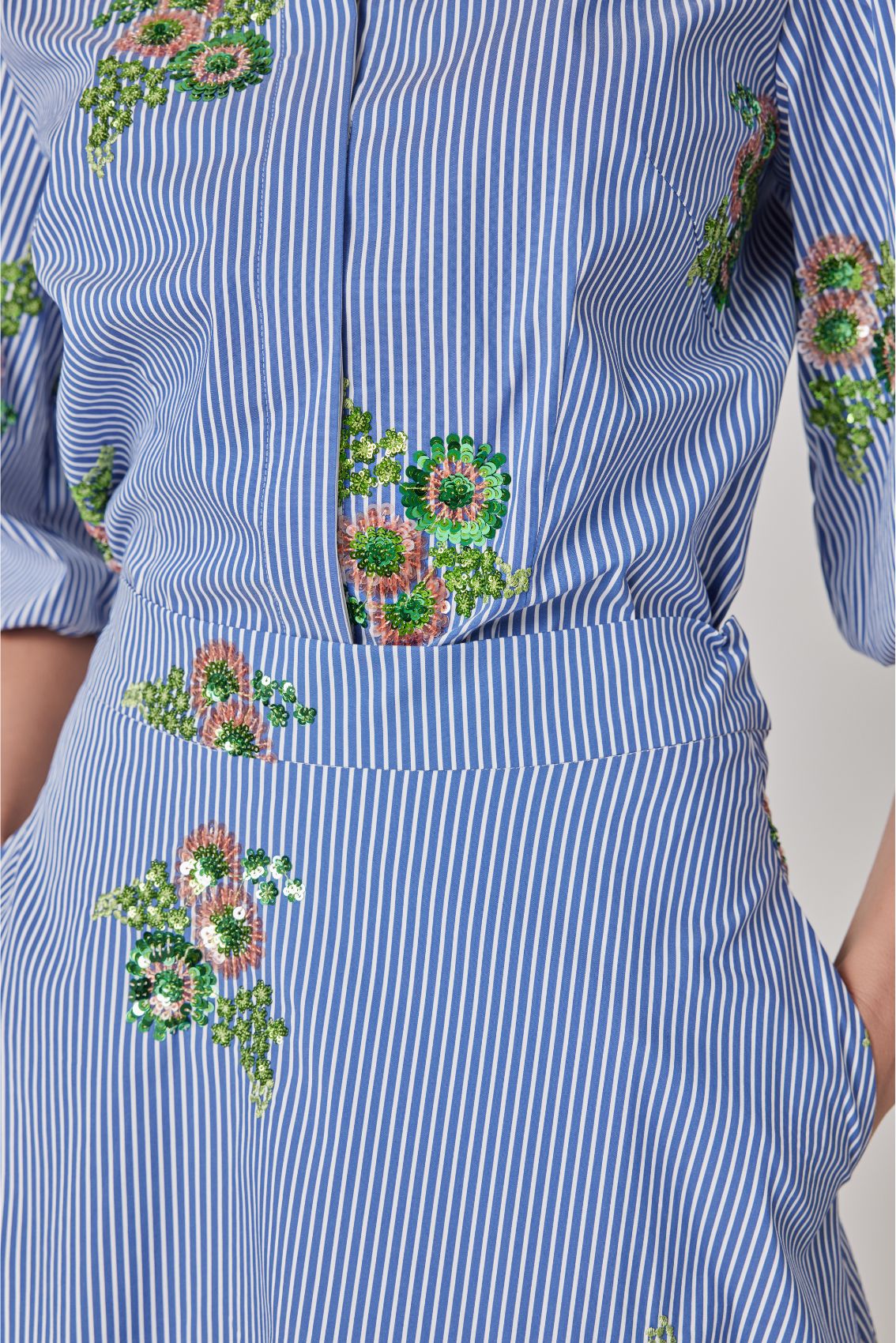 Detailaufnahme der Paillettenblüten auf blau-weißen Streifen der Bluse, Struktur und Schimmer sichtbar.