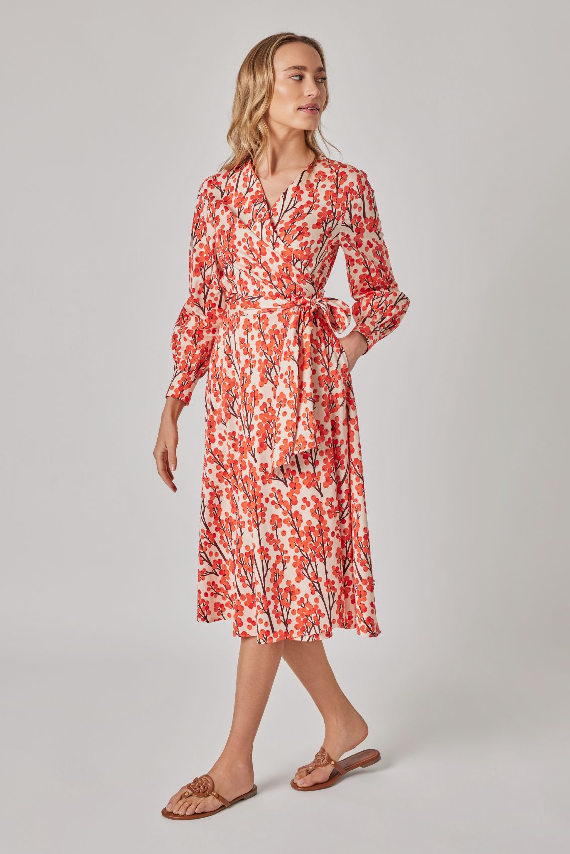 Model trägt Wickelkleid Sanddorn, Seitenansicht mit taillenbetonter Wicklung und Midi-Länge.