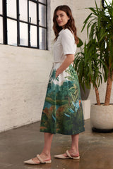 Modell in Seitenansicht trägt einen Blusenkleid mit Palmen-Print