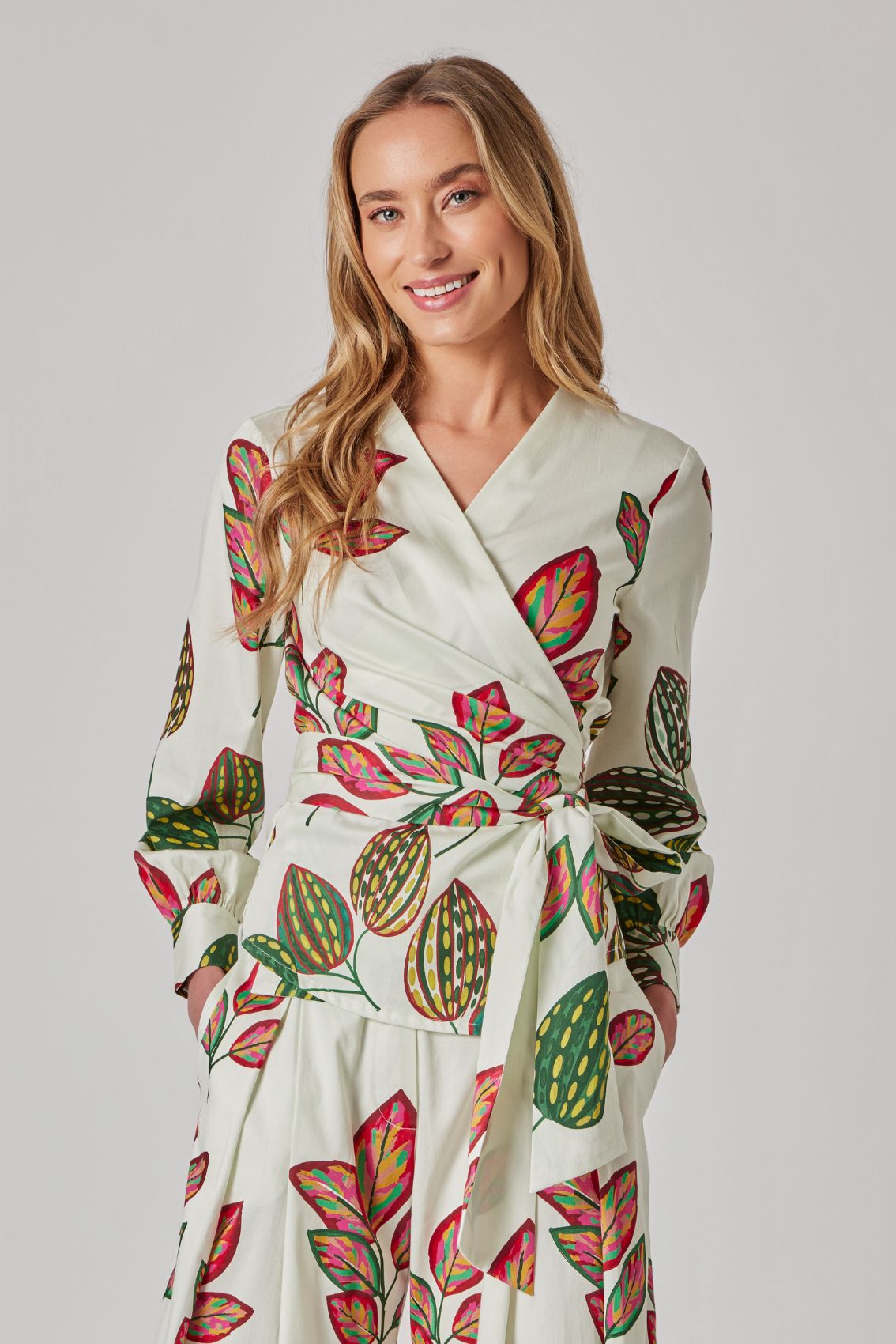 Model trägt helle High-Waist Hose mit weitem Bein und buntem Blätter-Print, Frontansicht.