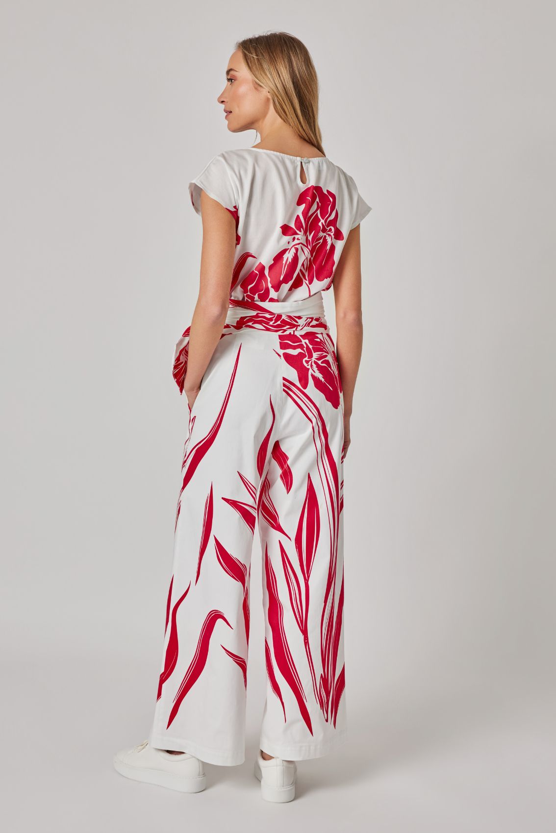 Model trägt weiße High-Waist Hose mit weitem Bein, Rückenansicht mit rotem Print und hohem Bund.