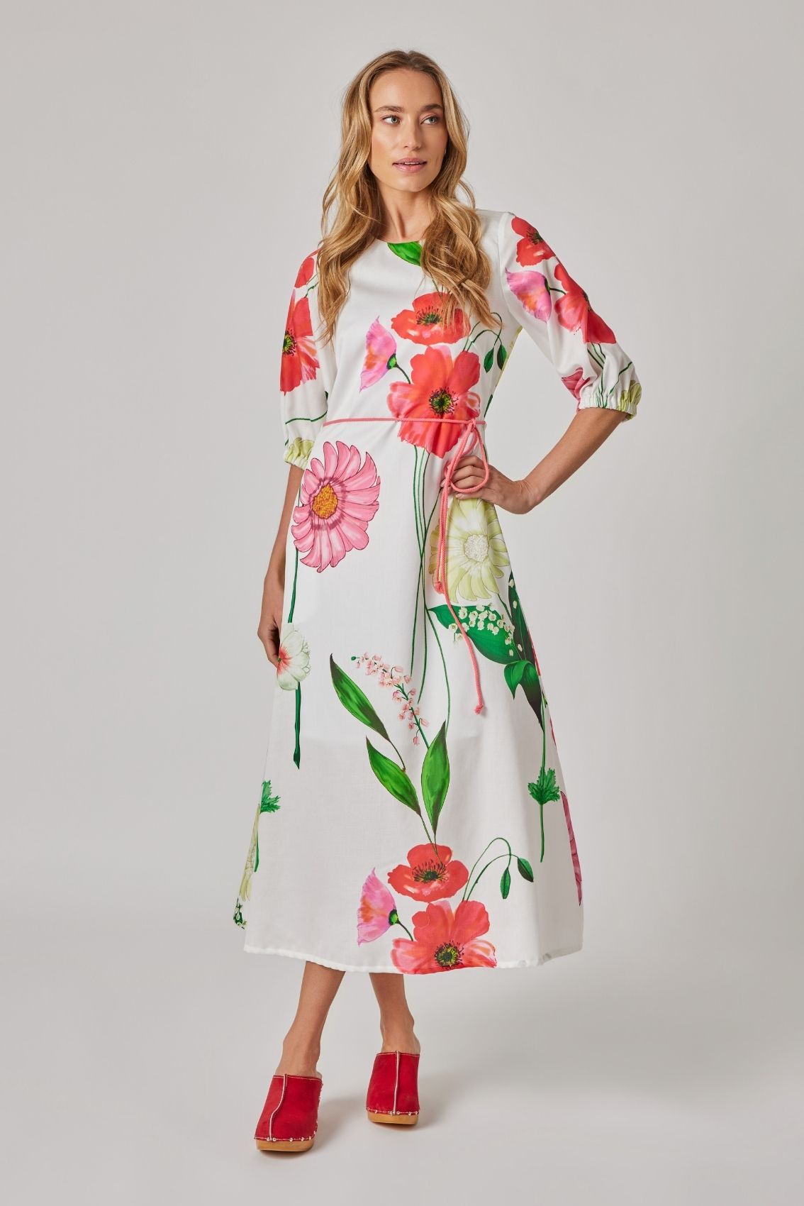 Model trägt florales Midikleid mit rundem Ausschnitt, 3/4-Ärmeln und Taillenband, Frontansicht.