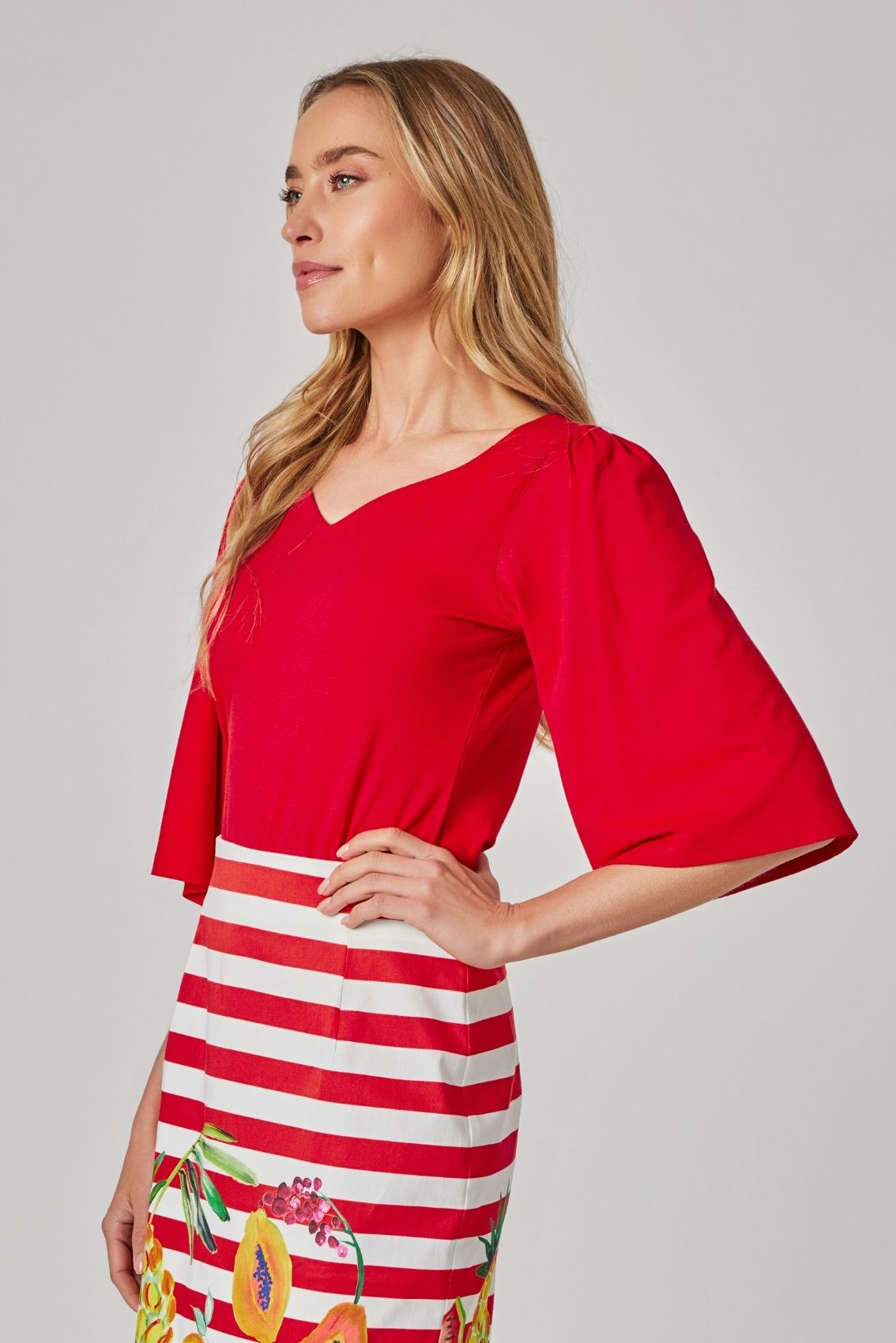 Model trägt rotes Shirt mit Herz-Ausschnitt und weiten Ärmeln, Seitenansicht