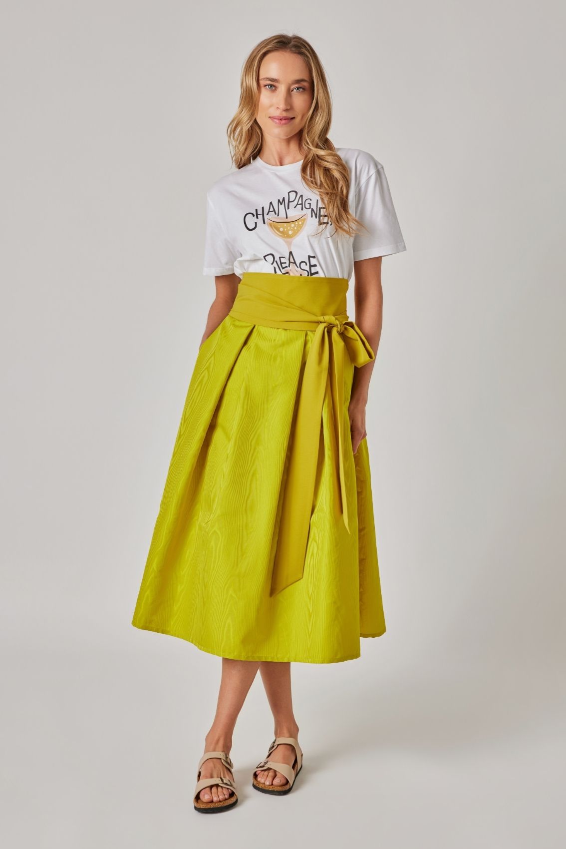 Model trägt Midirock in Lemon mit Kellerfalten und Moiré-Struktur, Frontansicht mit taillenbetontem Sitz.