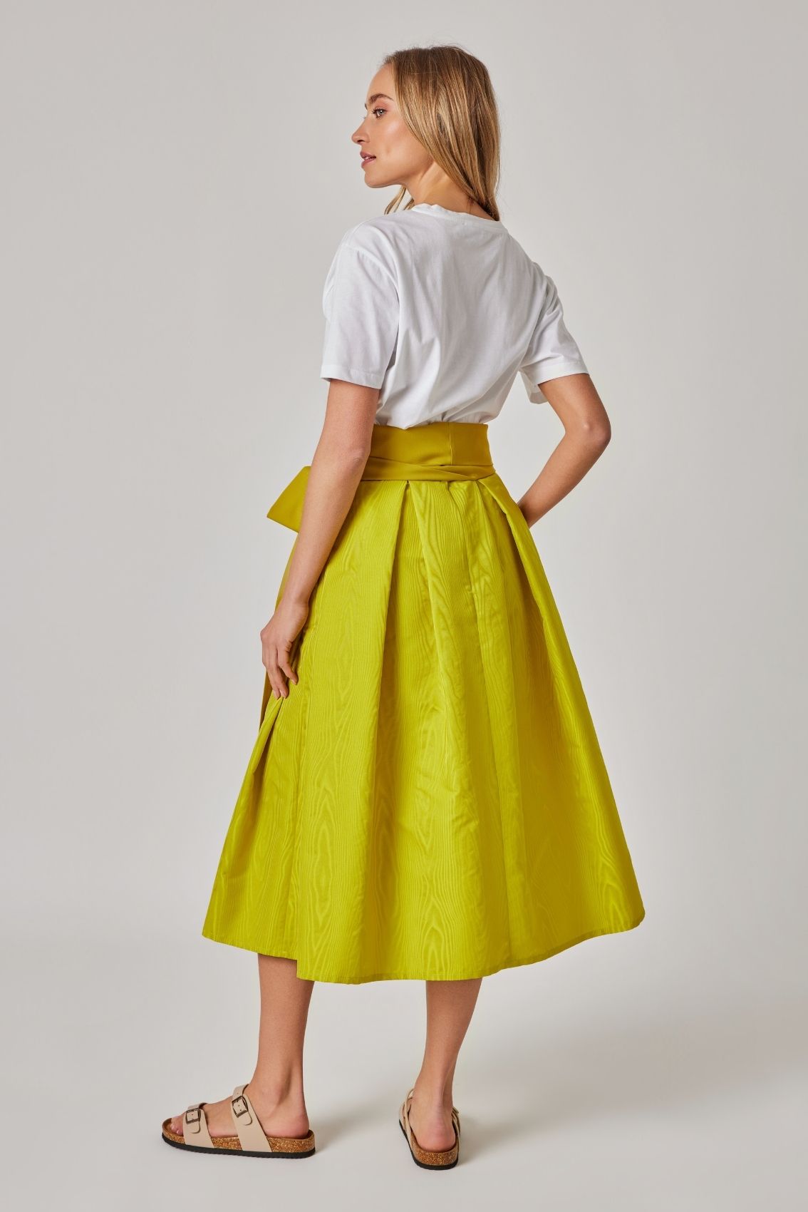 Model trägt Midirock in Lemon, Rückenansicht mit Reißverschluss hinten und weich fallender Silhouette.