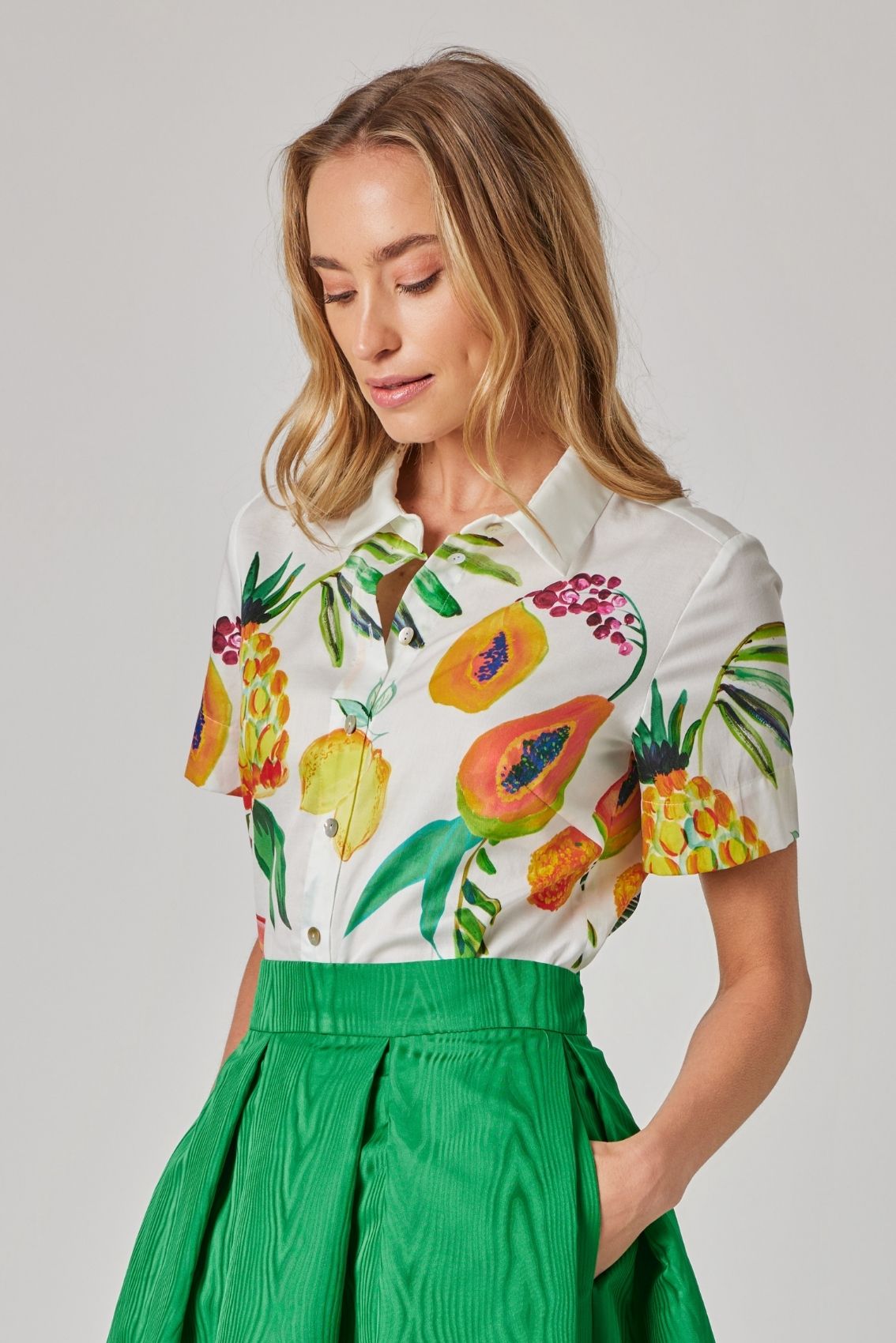 Model trägt Hemdbluse mit tropischem Print in Seitenansicht, mit leicht gerundetem Saum und lockerem Fall.