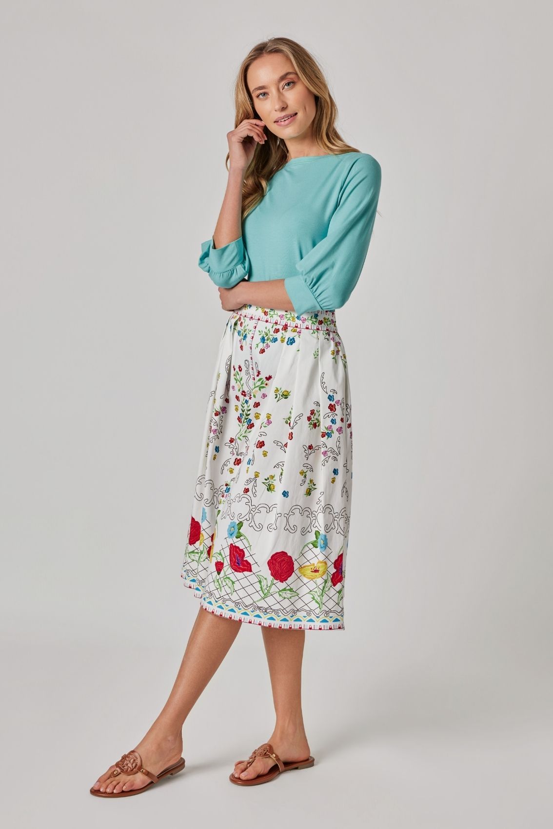 Model trägt Midirock mit Blumenprint in A-Linie mit klassischer Taille, Seitenansicht.