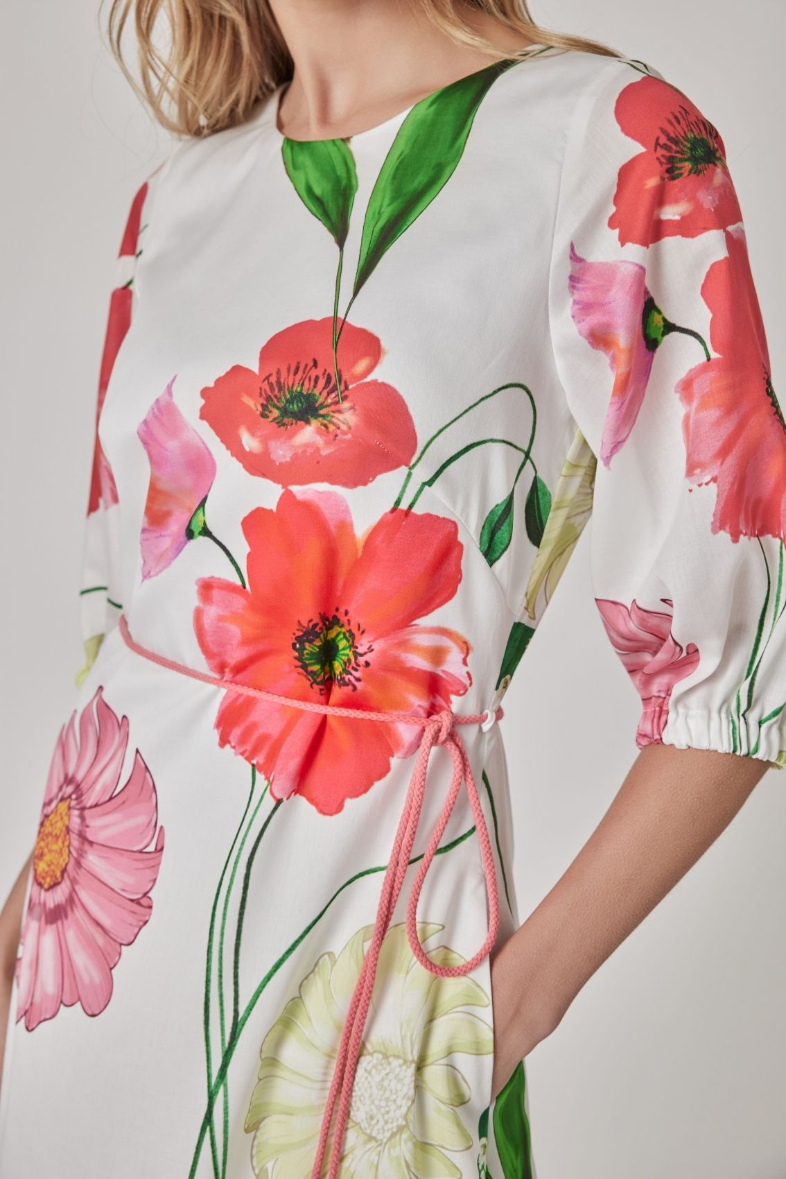 Detailansicht des floralen Prints auf hellem Fond mit korall-, rosa- und grünfarbenen Blüten.