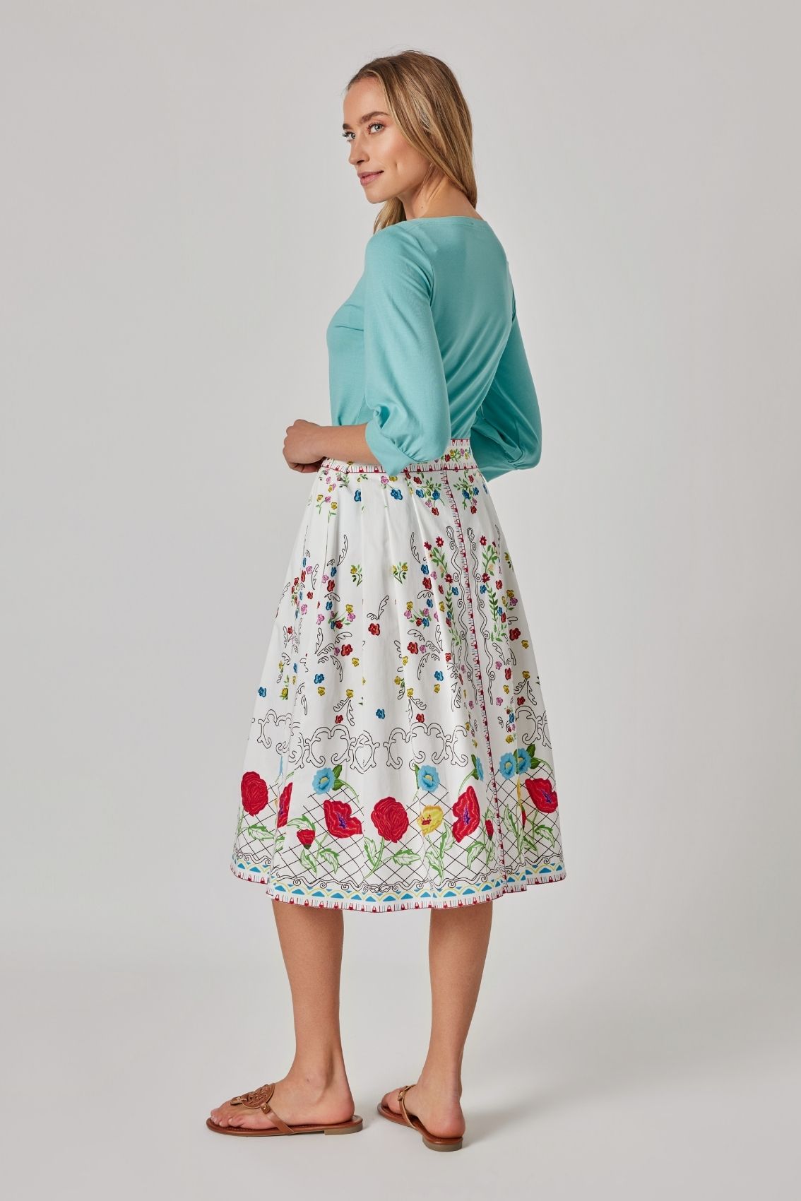 Model trägt Midirock mit Blumenprint mit Reißverschluss hinten und weich ausgestelltem Fall, Rückenansicht.