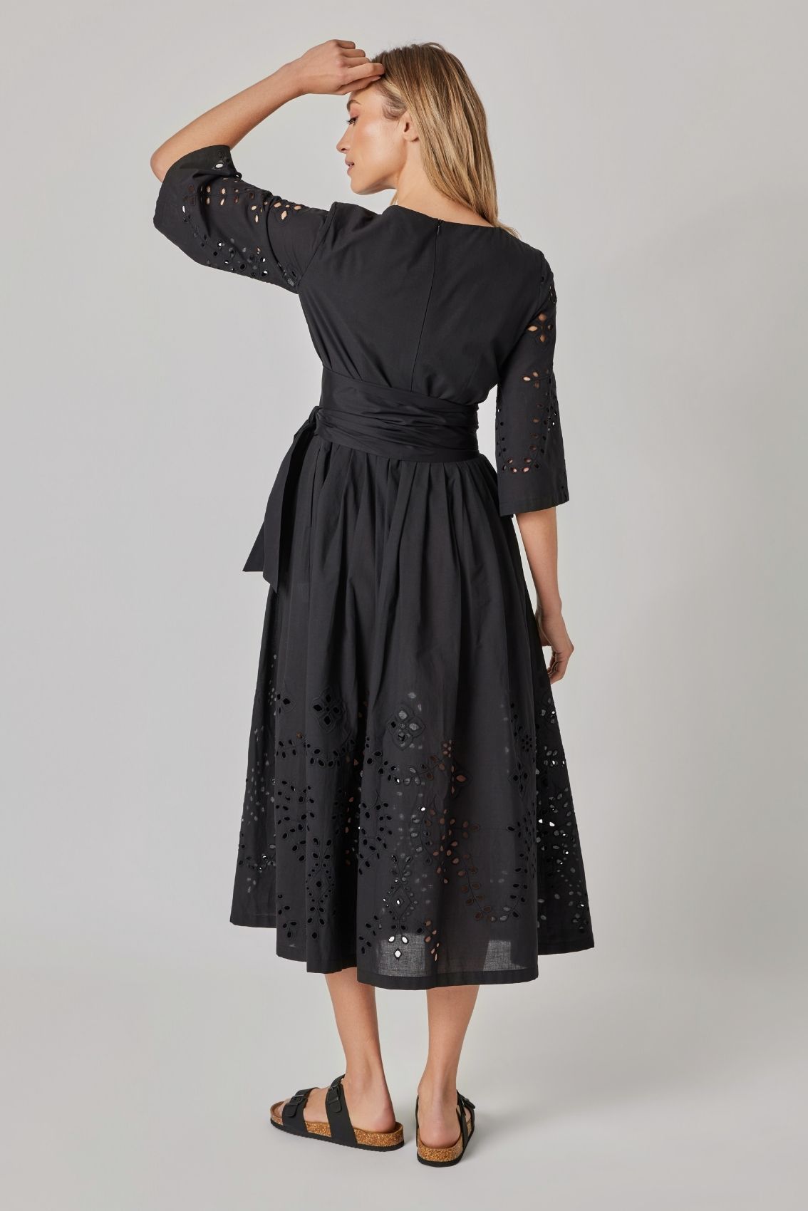 Model trägt schwarzes Midikleid mit Reißverschluss hinten und ausgestelltem Rock, Rückenansicht.