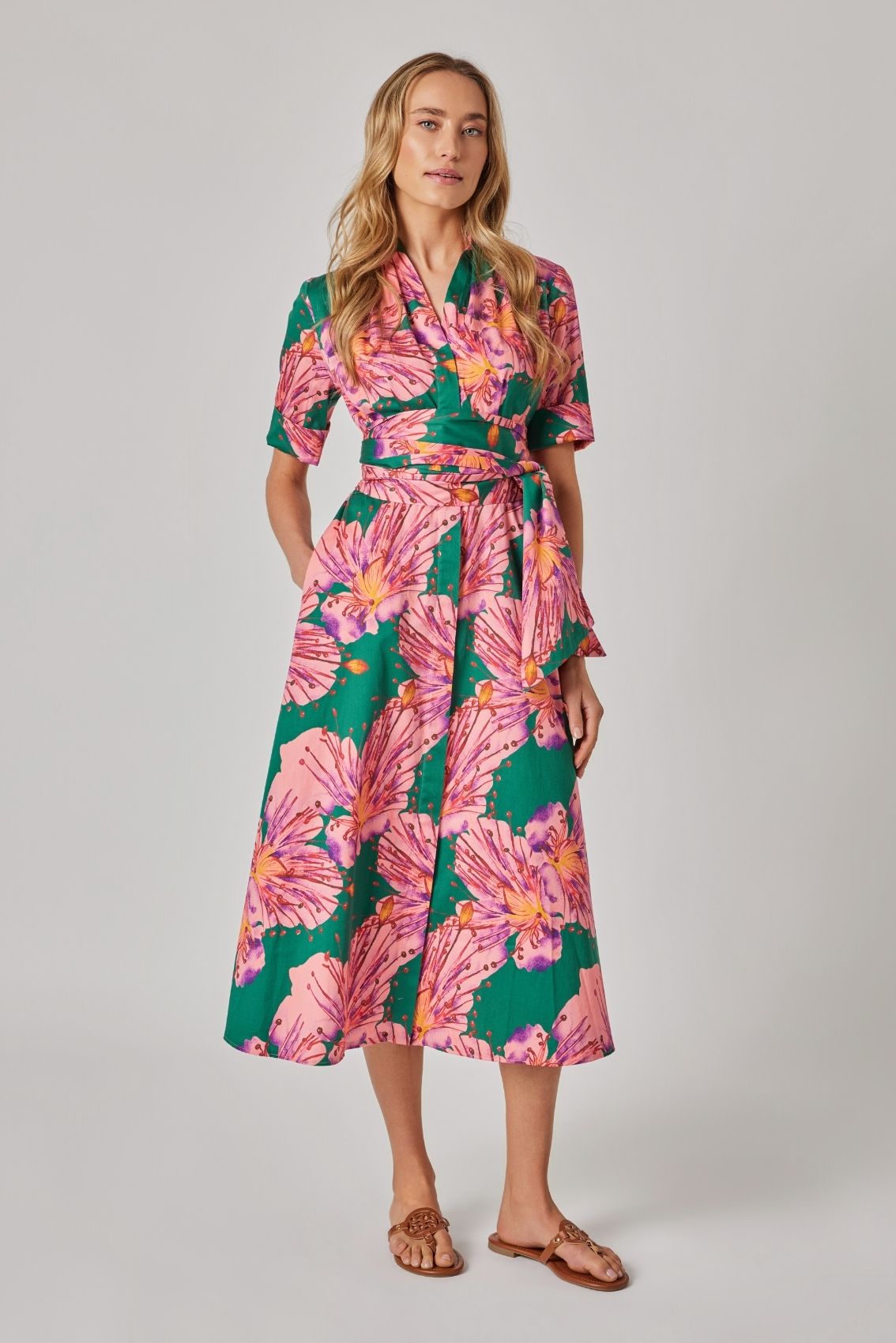 Model trägt florales Blusenkleid mit abnehmbarem Gürtel und Seitentaschen, Frontansicht mit taillierter Silhouette.