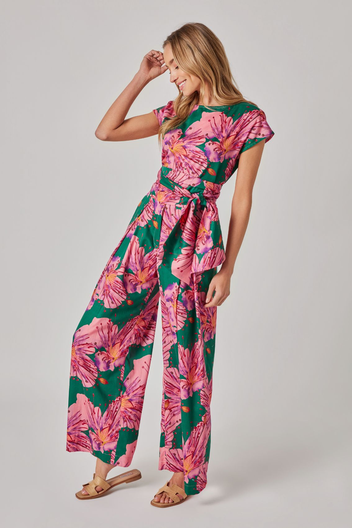 Model trägt grüne, weit geschnittene Hose mit floralem Print und Bindegürtel.