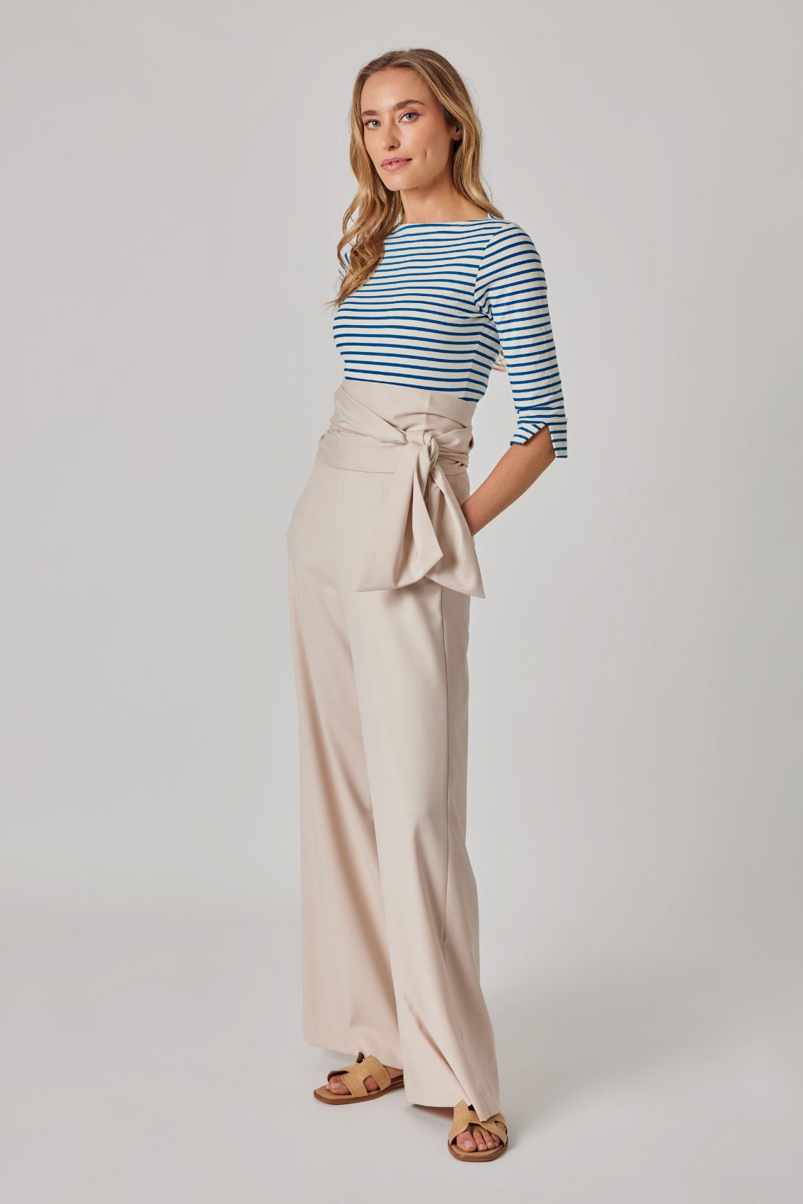 Model trägt gestreiftes 3/4-Arm Top und beige, weite Hose mit seitlichem Bindegürtel, Seitenansicht.