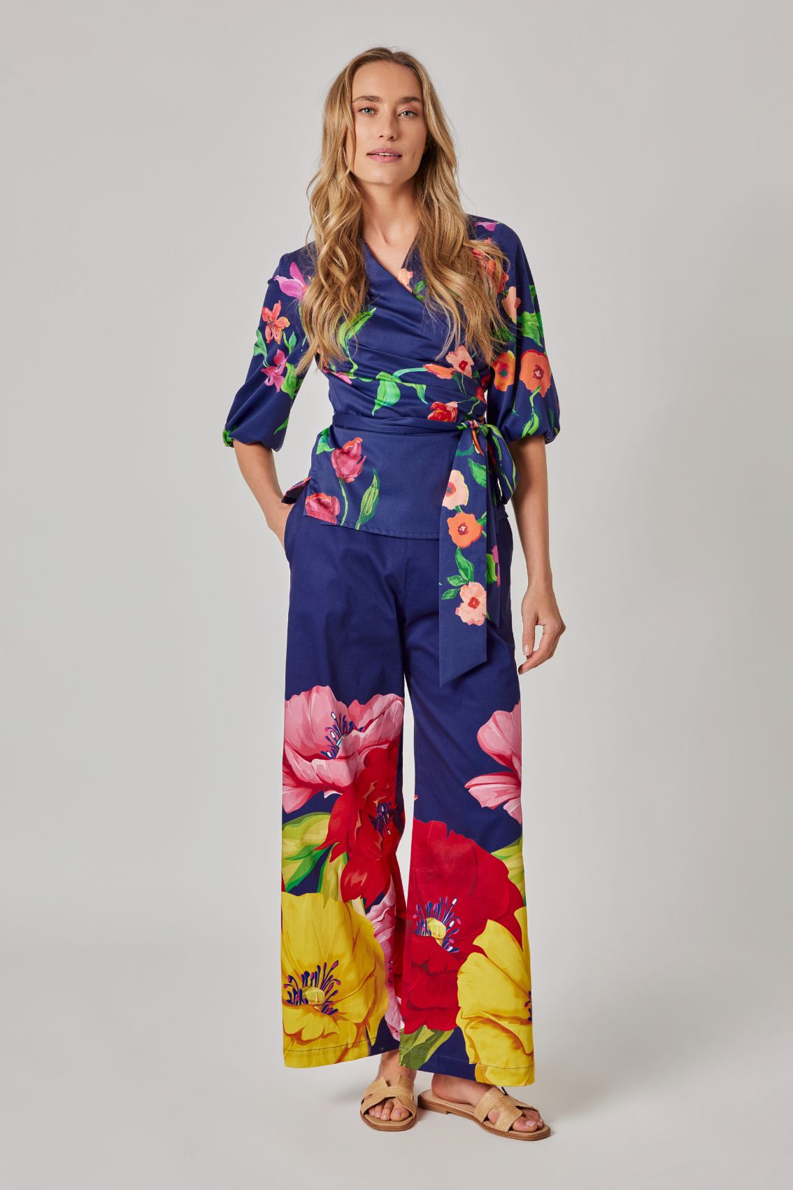 Model trägt dunkelblaue High-Waist Hose mit weitem Bein und großflächigem Blumenprint, Frontansicht.
